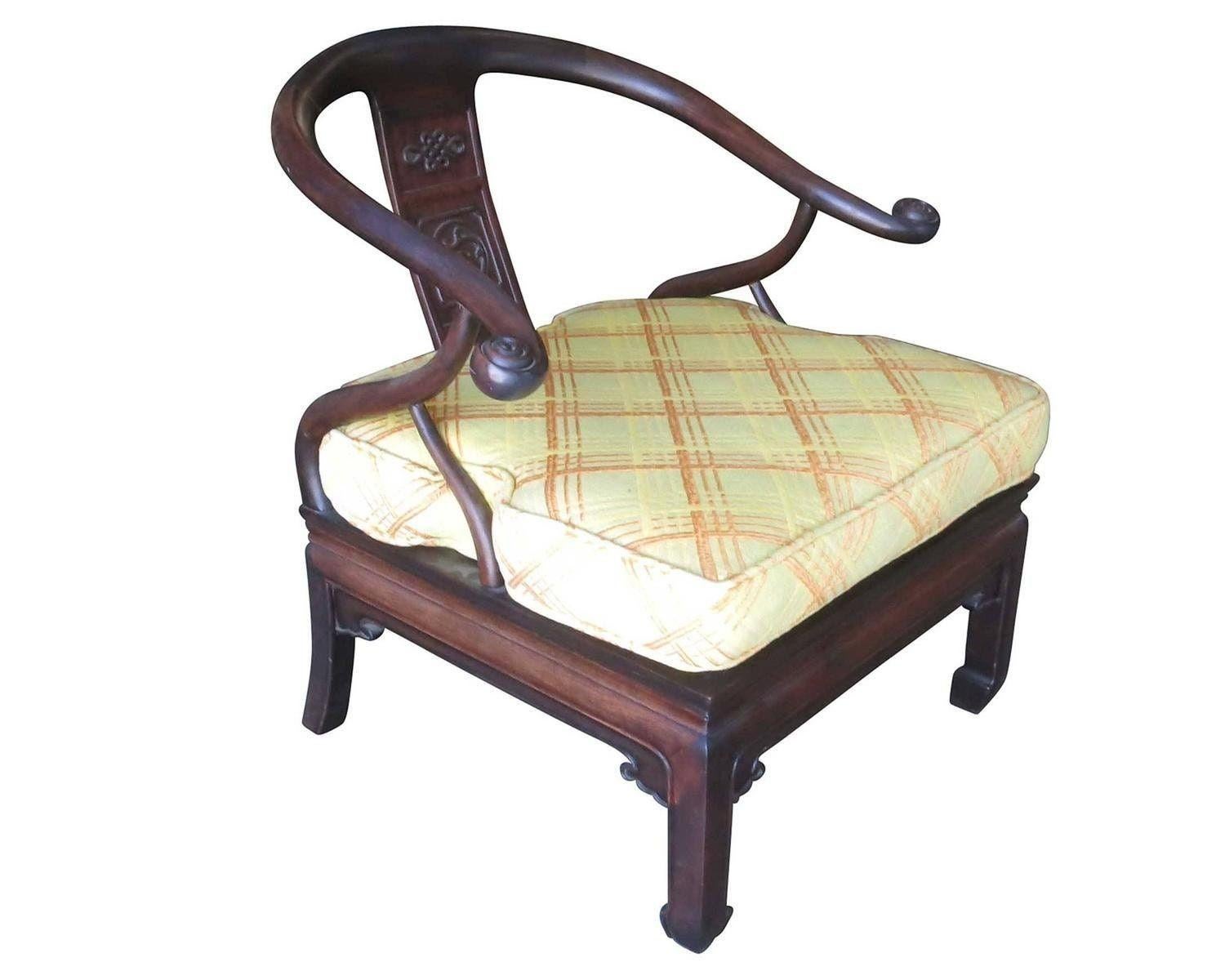 Superbe paire de fauteuils asiatiques en fer à cheval de style James Mont.

Les deux possèdent un cadre en bois teinté foncé avec des reliefs et des décorations sculptés à la main. Les coussins d'assise multicolores présentent un motif original de
