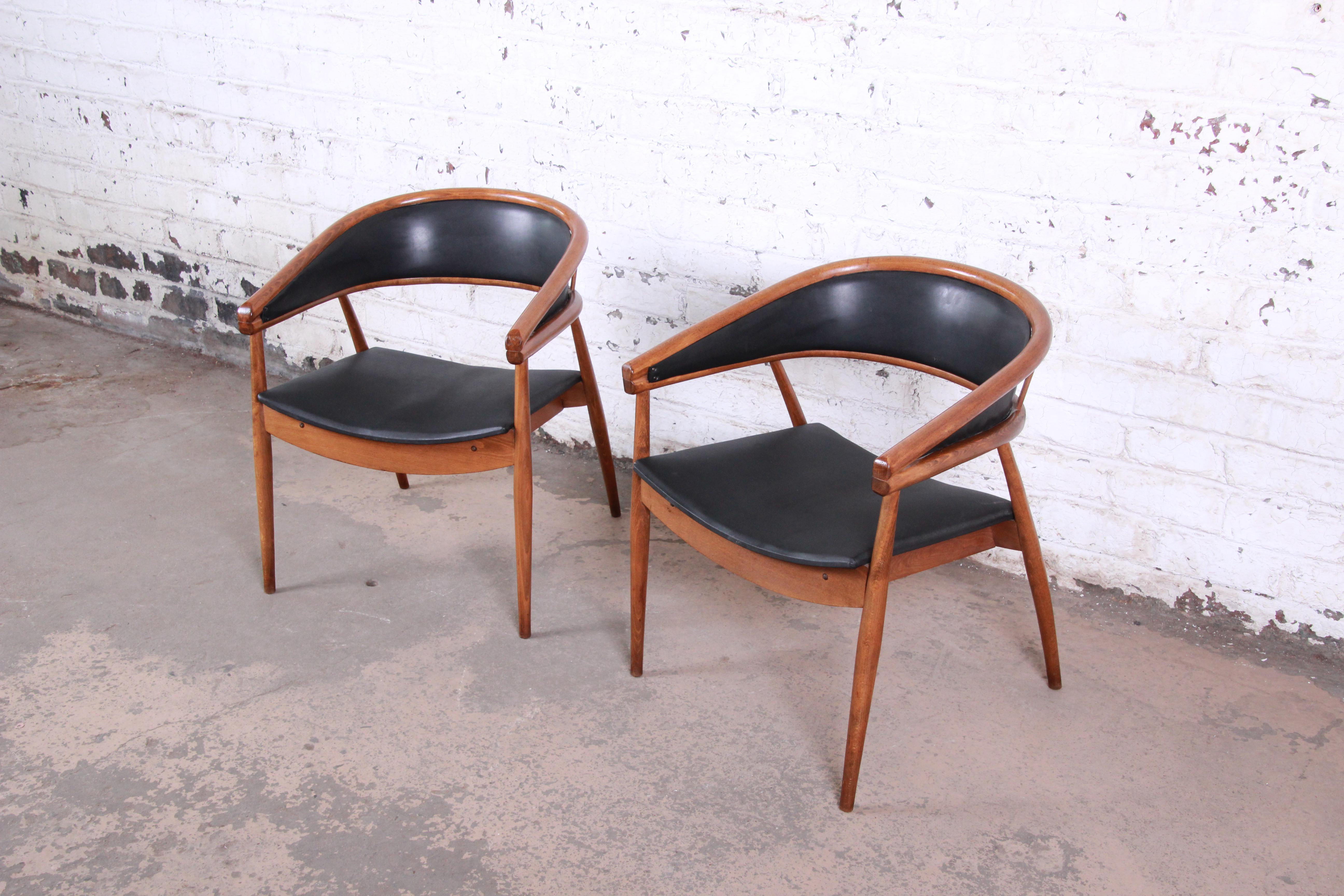 An exceptional pair of James Mont style bent beechwood club chairs. Mont famously used this design in Nat King Coles' Miami Penthouse project. The chairs feature a stunning bentwood design and original black vinyl upholstery. The chairs are in very