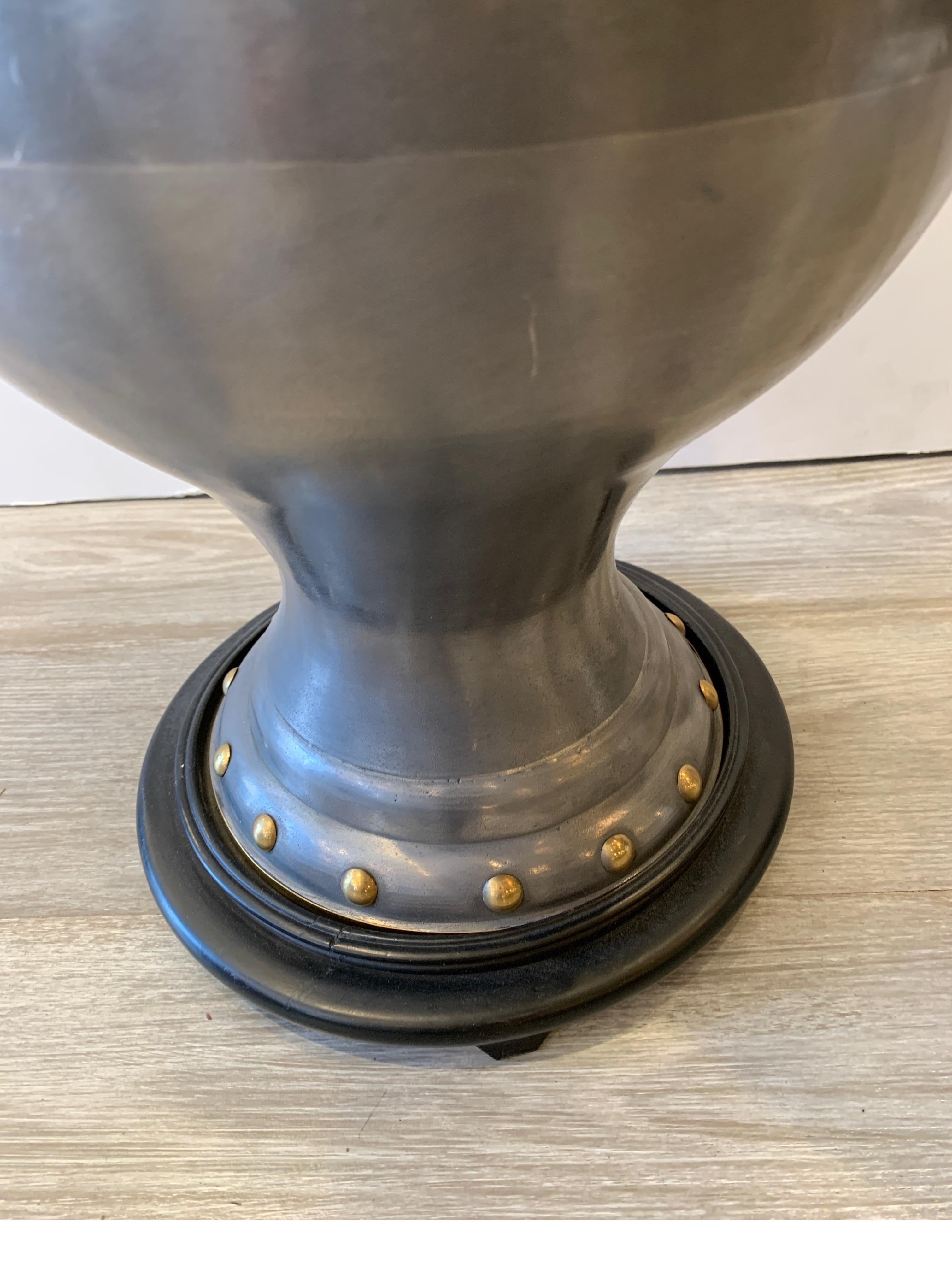 The bulbous shape with brass rings and rivets on a black wood base. The Asian theme in the manner of James Mont. The shade is for photographic purposes only and not included. The height with a shade is 38