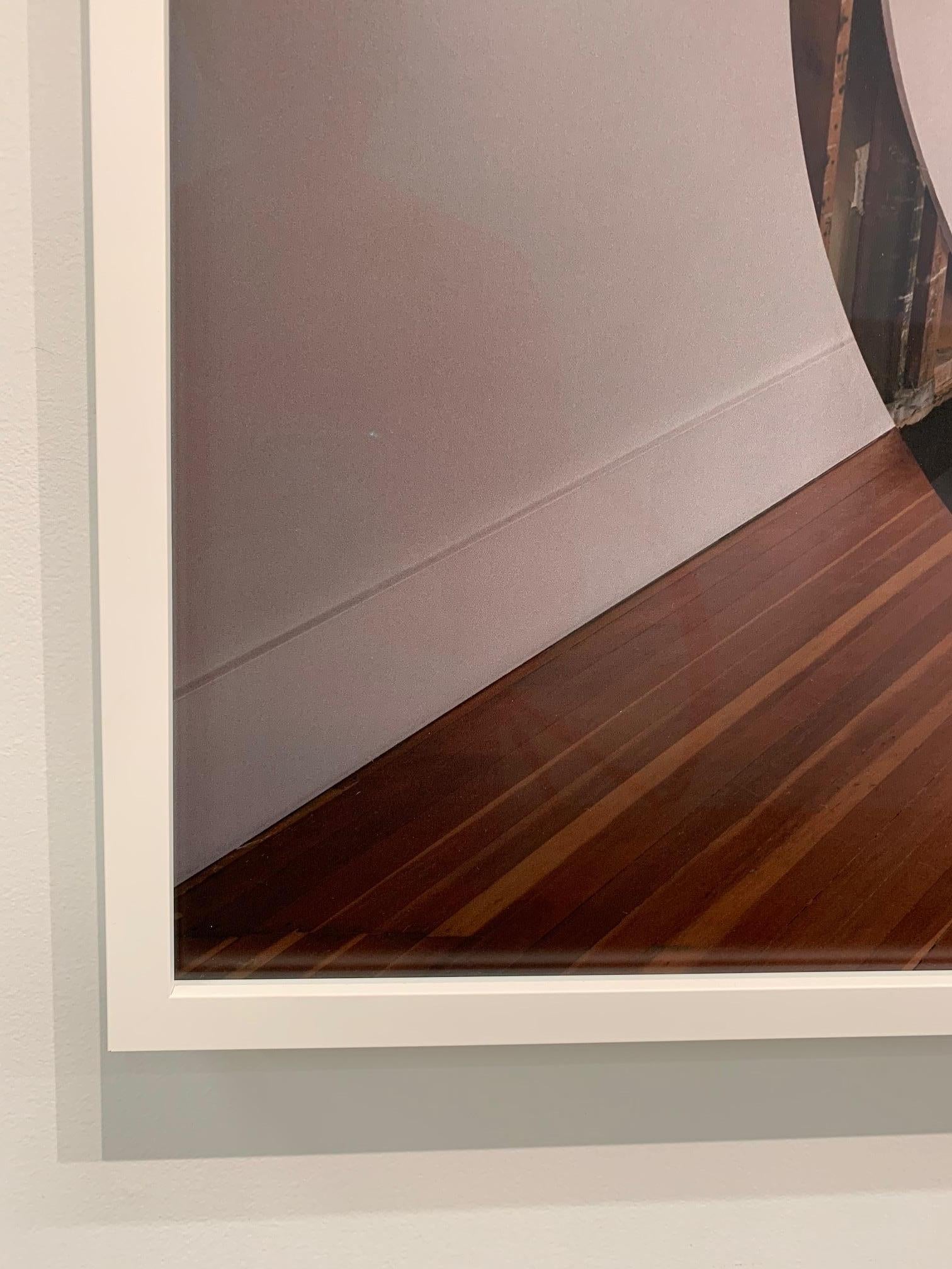 This contemporary, abstract, architectural, optical, photograph depicts an illusion of a floating ellipse, however the ellipse shape physically exists. The artists carefully cut the shape out of the floors, walls and ceiling, and at the exact point