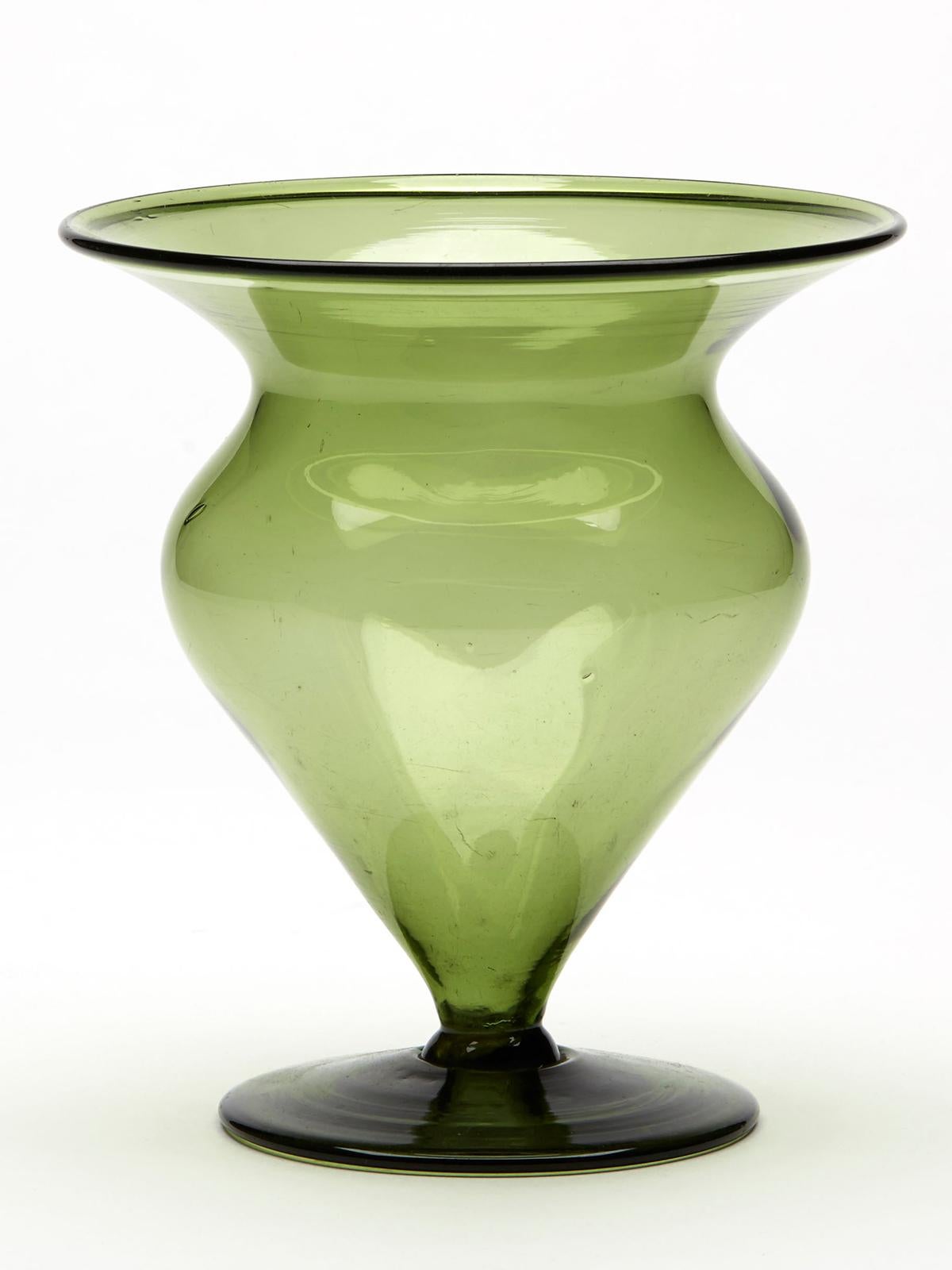 An absolutely stunning Arts & Crafts bud shaped art glass vase attributed to renowned glass maker Harry James Powell (British, 1853 - 1922) and dating from around 1900. The vase hand blown in a green tinted glass stands on a wide round foot rim with