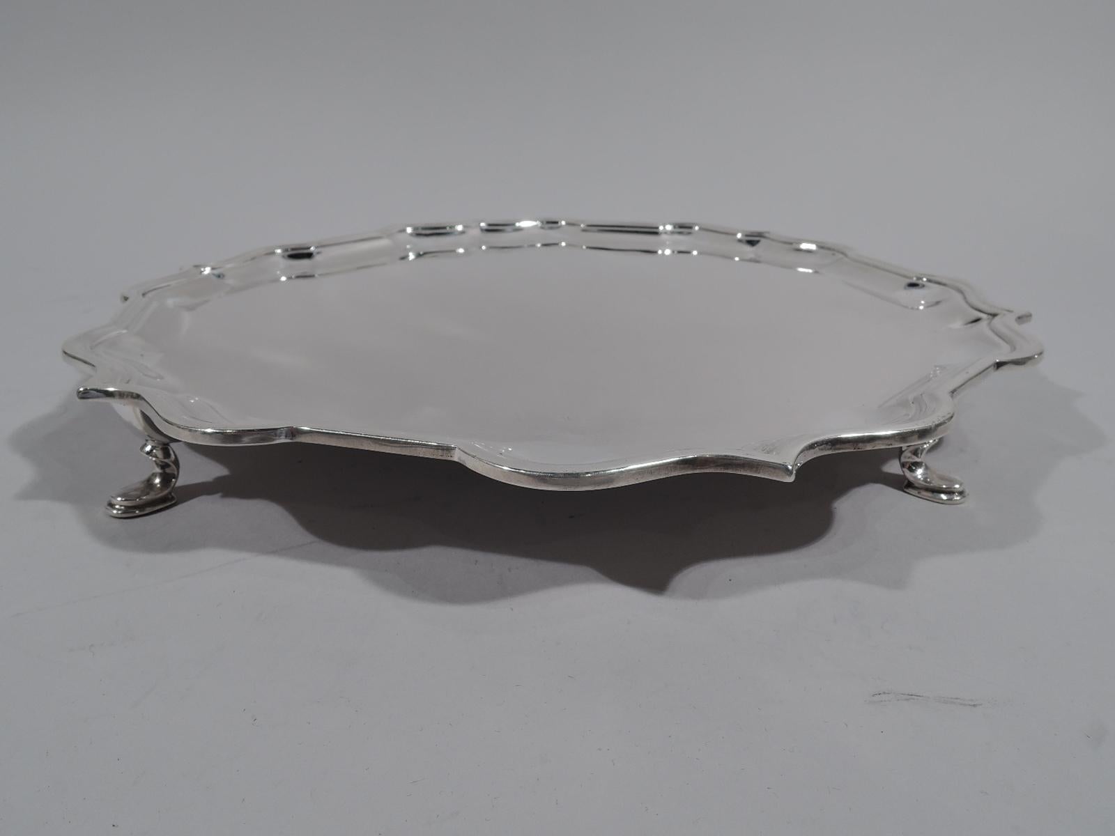 Traditional Georgian sterling silver salver. Made by Roberts & Belk in Sheffield in 1974. Round with molded curvilinear piecrust rim. Rests on 4 padded hoof supports. English marks and New York retailer’s stamp (James Robinson). Weight: 25 troy