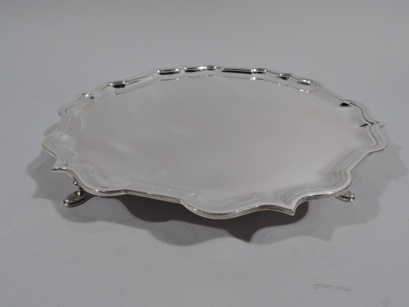 Traditional Georgian sterling silver salver. Made by Roberts & Belk in Sheffield in 1974. Round with molded curvilinear piecrust rim. Rests on 4 padded hoof supports. Fully marked including maker’s and New York retailer’s stamp James Robinson.
