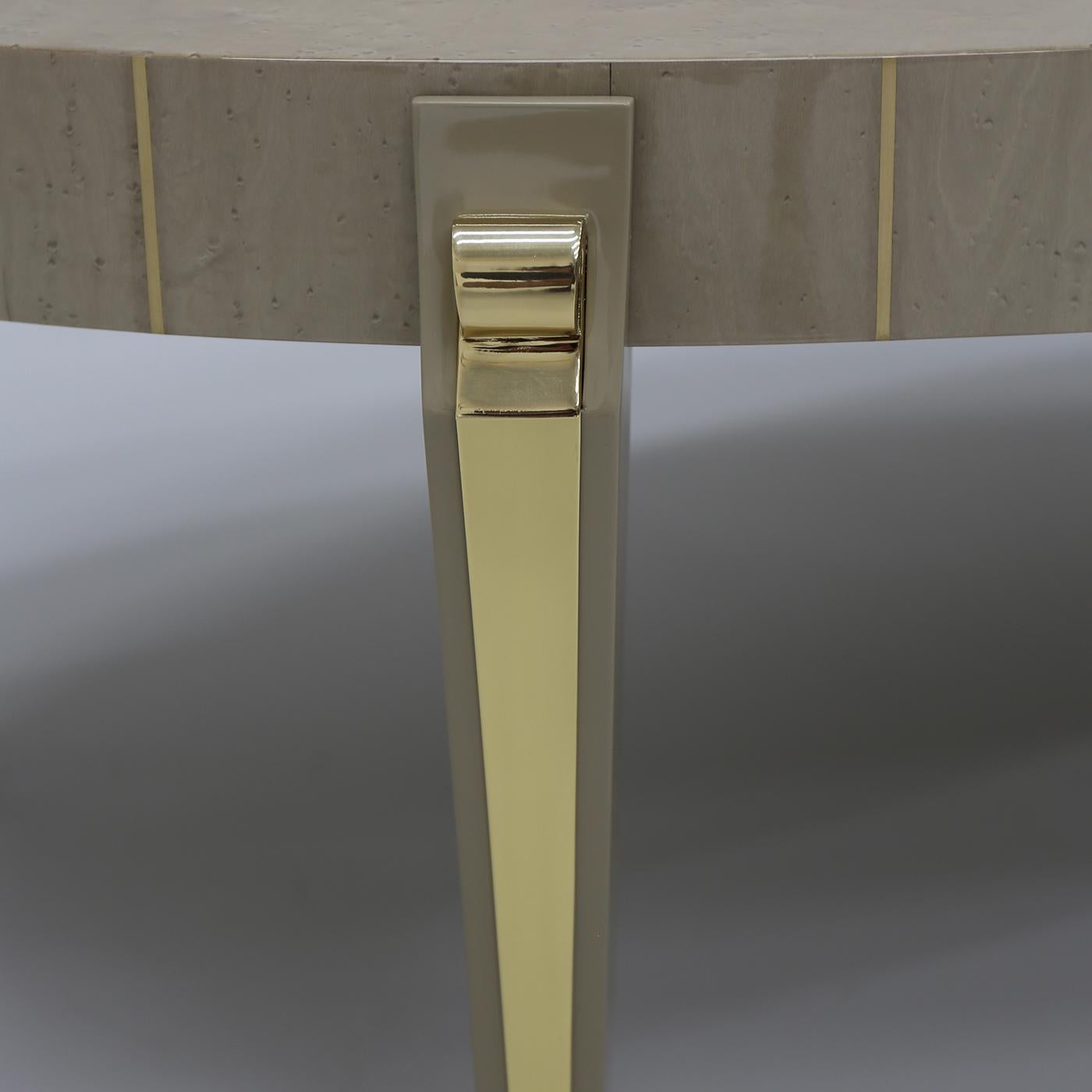 Ajoutez une dose d'élégance à un salon moderne avec la table d'appoint ronde James. Fabriquée en bois de hêtre, la table est peinte, ici dans un ton beige, et rehaussée de métal doré. Mélangeant diverses influences, la table se distingue par ses
