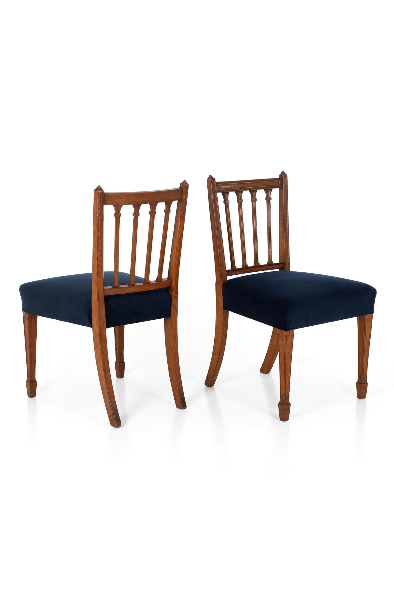A wonderful pair of James Shoolbred occasional chairs in mahogany.

The gothic style chairs have a square back with four vertical slats.

Featuring Marlborough front legs and sabre legs to the rear.

Freshly reupholstered in dark indigo velvet, with