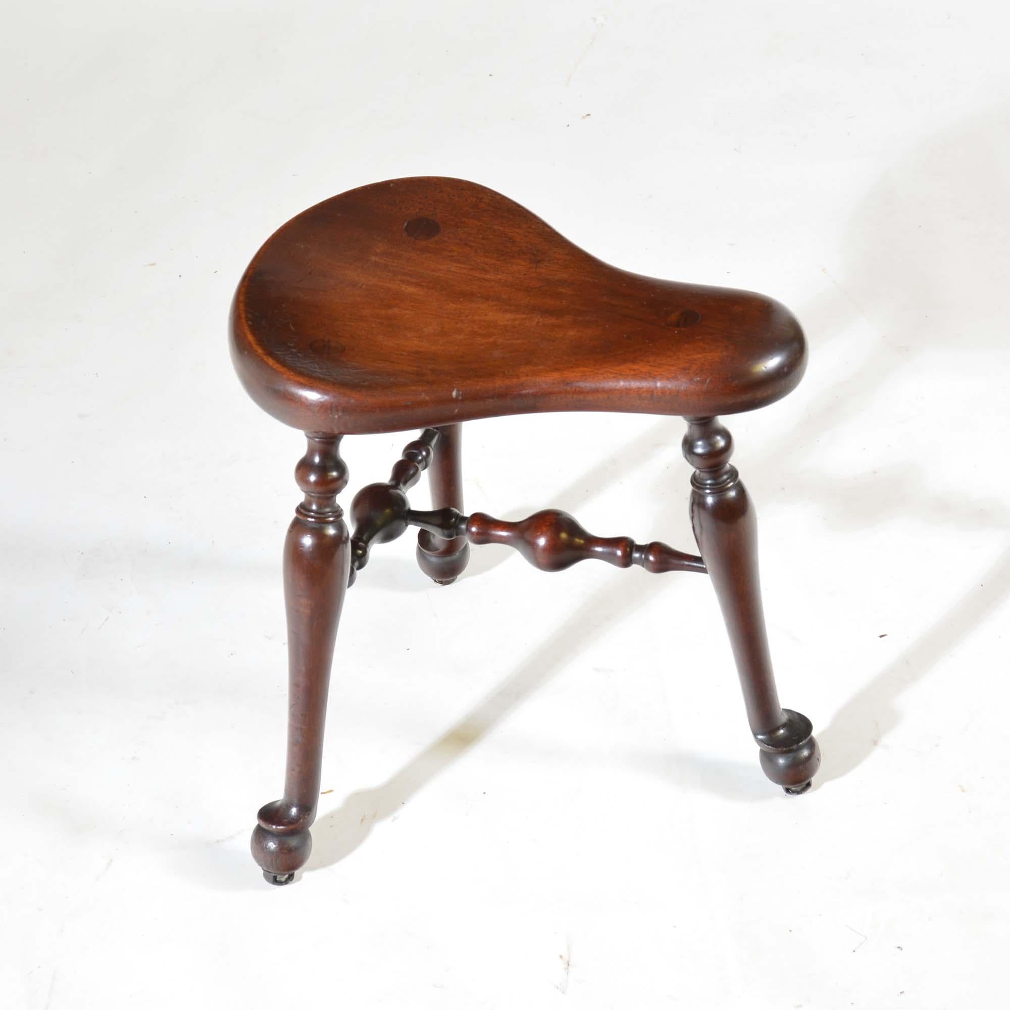 James Shoolbred saddle seat walnut three legged cock-fighting stool
Saddle seat over baluster turned legs united by stretchers. Stands on steel castors.
By James Shoolbred, London, impressed registration No. 222356 which dates it to 1893-4.
English,