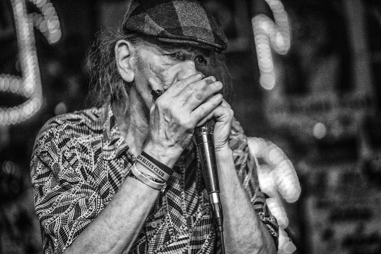 Wassermelone Slim in Rottönen 2023

Eine Schwarz-Weiß-Fotografie des düsteren Bluesmusikers Watermelon Slim in der Reds Bar in Clarksdale, Mississippi.  Watermelon Slims gefühlvoller und kathartischer Gesang, sein sanftes Spiel auf der Slide-Gitarre