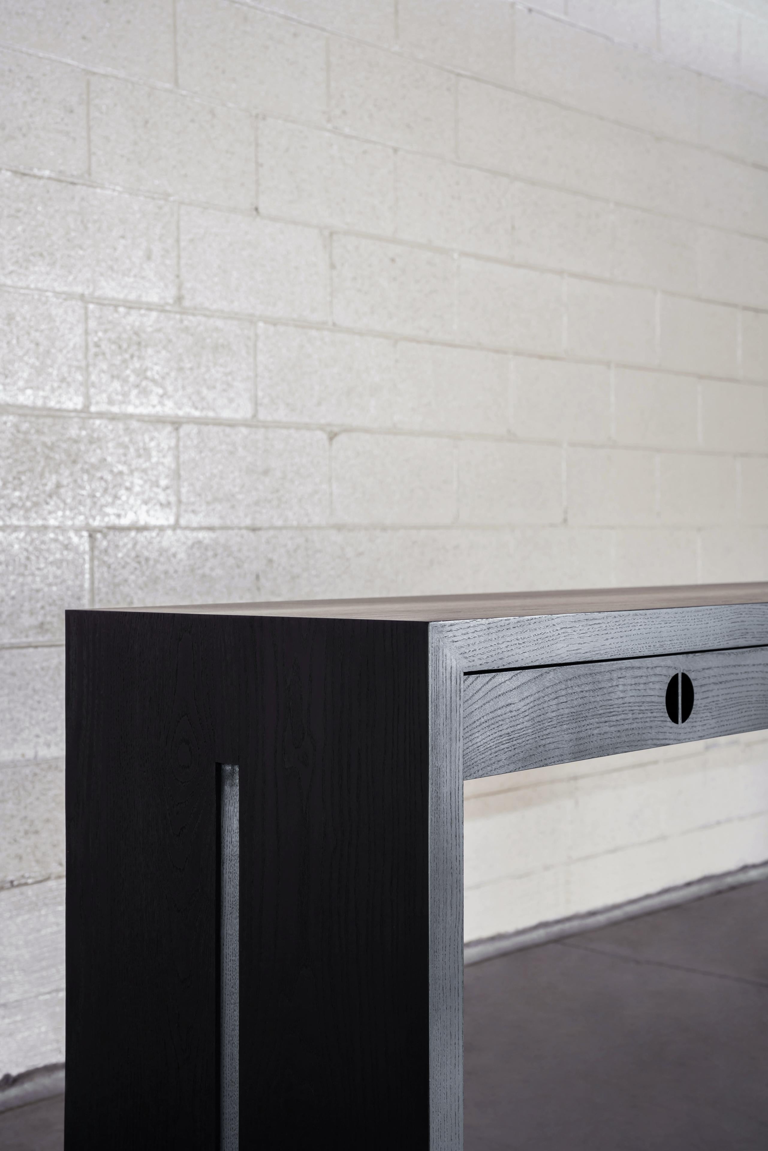 This custom wood console table is hand-made in the United States with all hardwood construction. It features a modern design with a solid ash body and a gorgeous matte black finish. Convenient and accessible storage drawers feature integrated