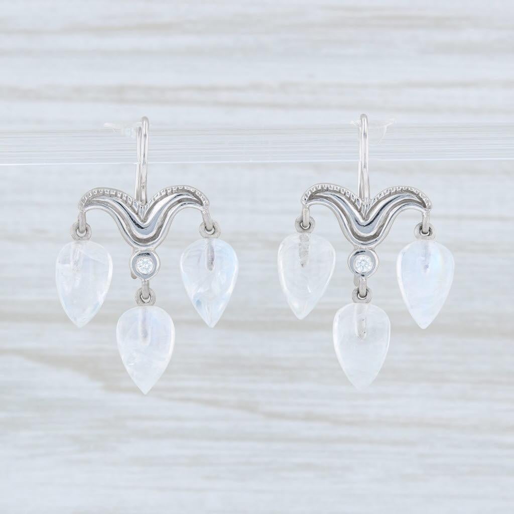 These lovely earrings are a Jamie Wolf design. Each earring has an ornate flourish accented by genuine diamonds and connecting moonstone dangles. Each moonstone has a ribbon like accenting with a blue flash and rainbow hues.

Gem: Natural Diamonds -