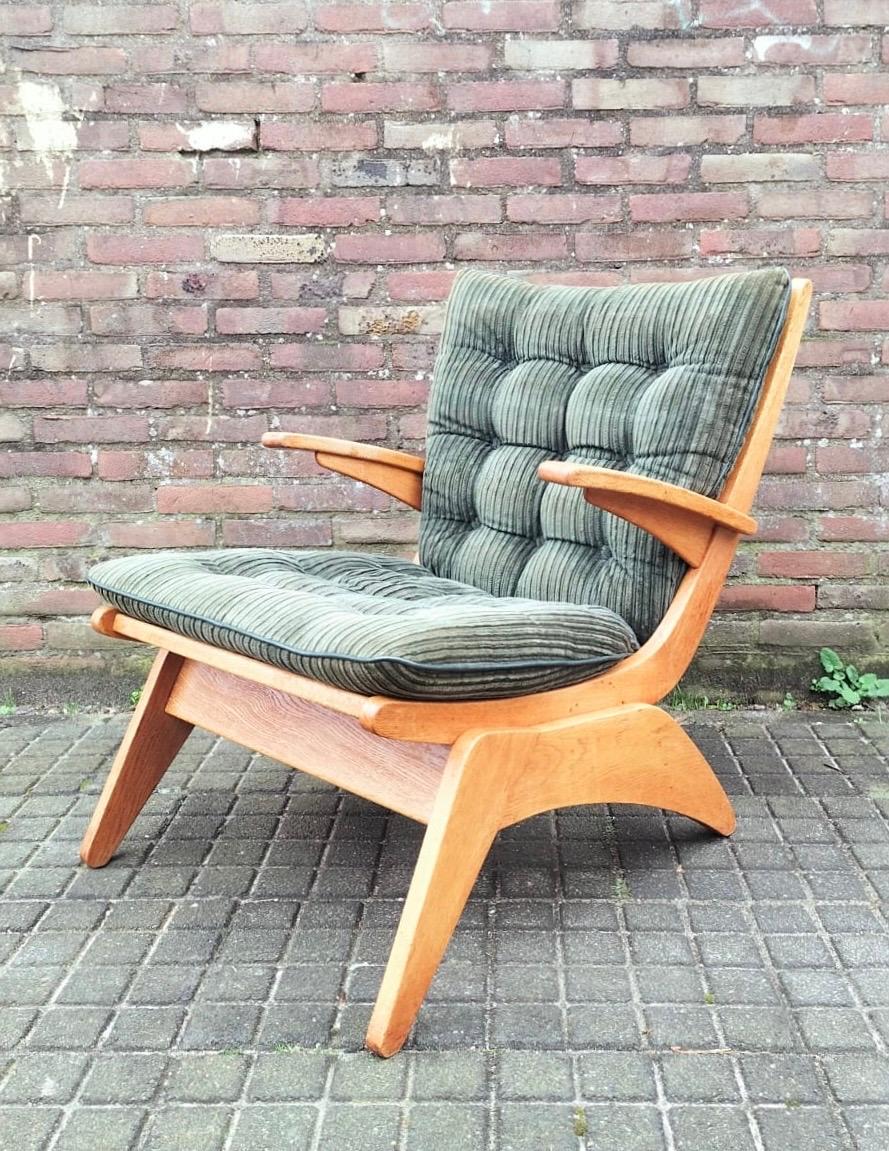 This early Dutch Mid-Century armchair was designed by Jan den Drijver, Ca. the 1940s and features a distinctive frame made from solid Oak.  The Moss green fabric is complimenting the colour of the wood. The comfortable cushion features a leatherette