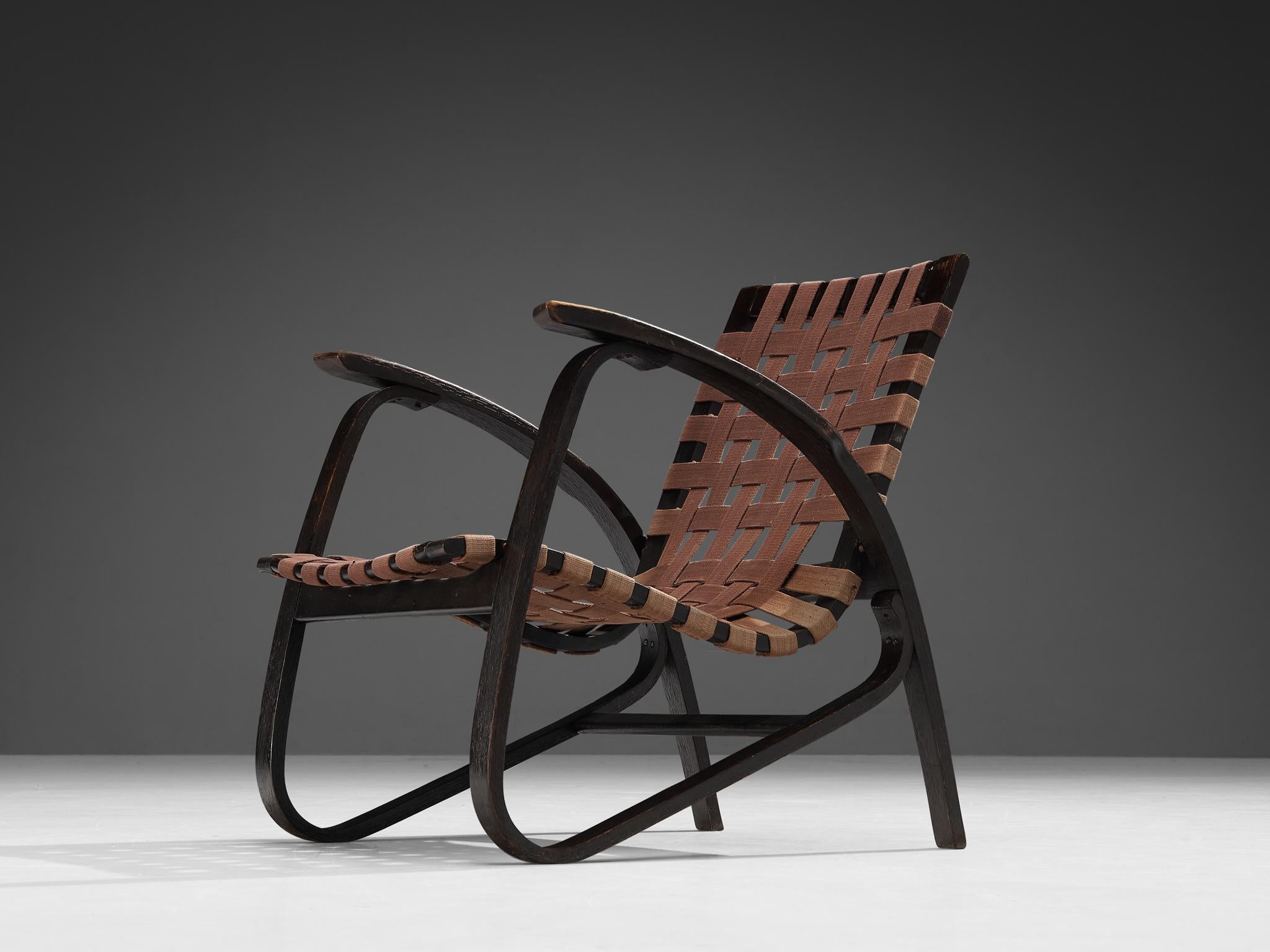 Jan Vanek for UP Zavodny, lounge chair, canvas, stained wood, Czech Republic 1930s. 

This armchair by Jan Vanek, a contemporary of Jindrich Halabala, embodies a dynamic appearance that, for instance, comes forward in the organic, curved shaped