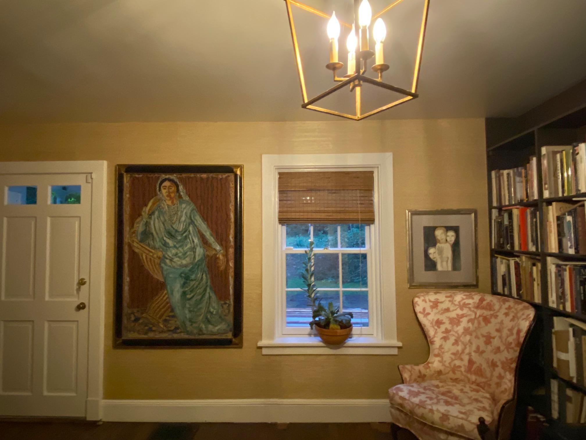 A Beautiful Indian woman in a flowing green sari is seated in an exotic chair.  The blue and cream rug set off the red and blue background behind her.  
Beautifully framed with a black carved wood frame with gold leaf corners.  