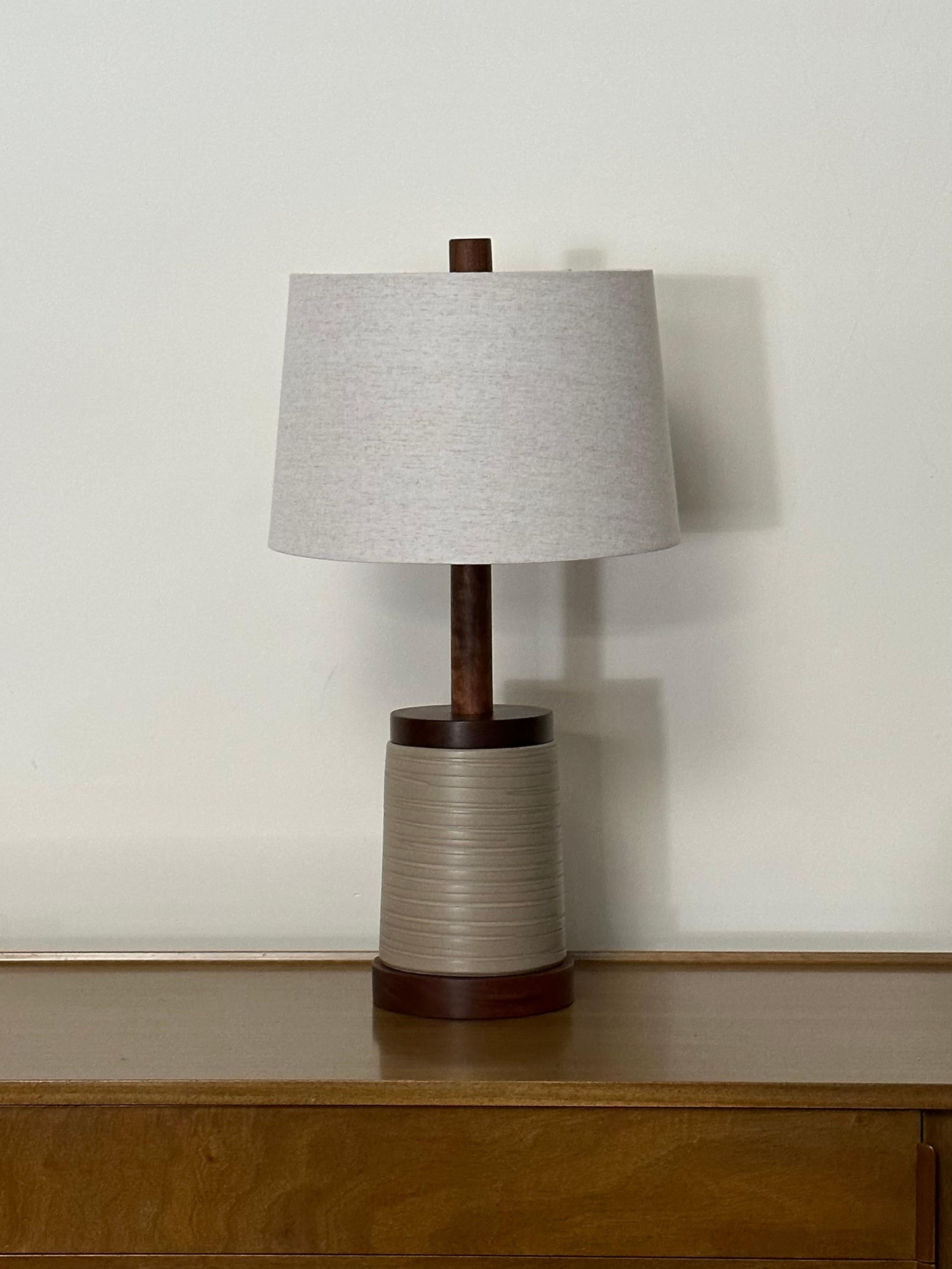 Gorgeous table lamp by the famed ceramicist duo Jane and Gordon Martz for Marshall Studios. Features a walnut disc base, ceramic body, and a walnut disc on top complete with long neck. Very attractive design and colors. 

Measures;
Overall;
28”