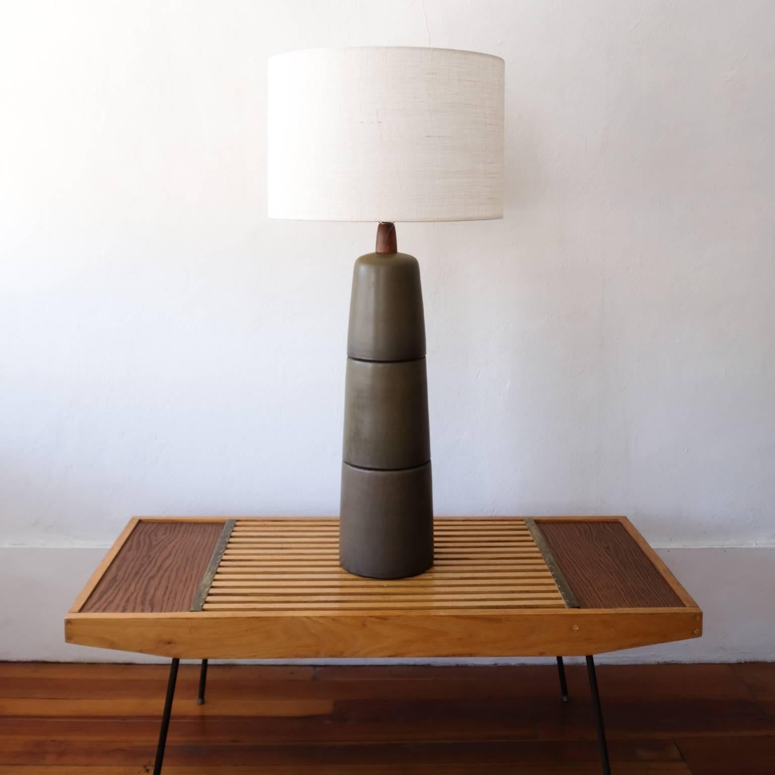 Monumental ceramic table lamp by Jane and Gordon Martz for their company, Marshall Studios. Segmented triple stack design with a dark olive glaze. Incredibly large original walnut finial. Signed in the clay and includes a Marshall Studios label. New