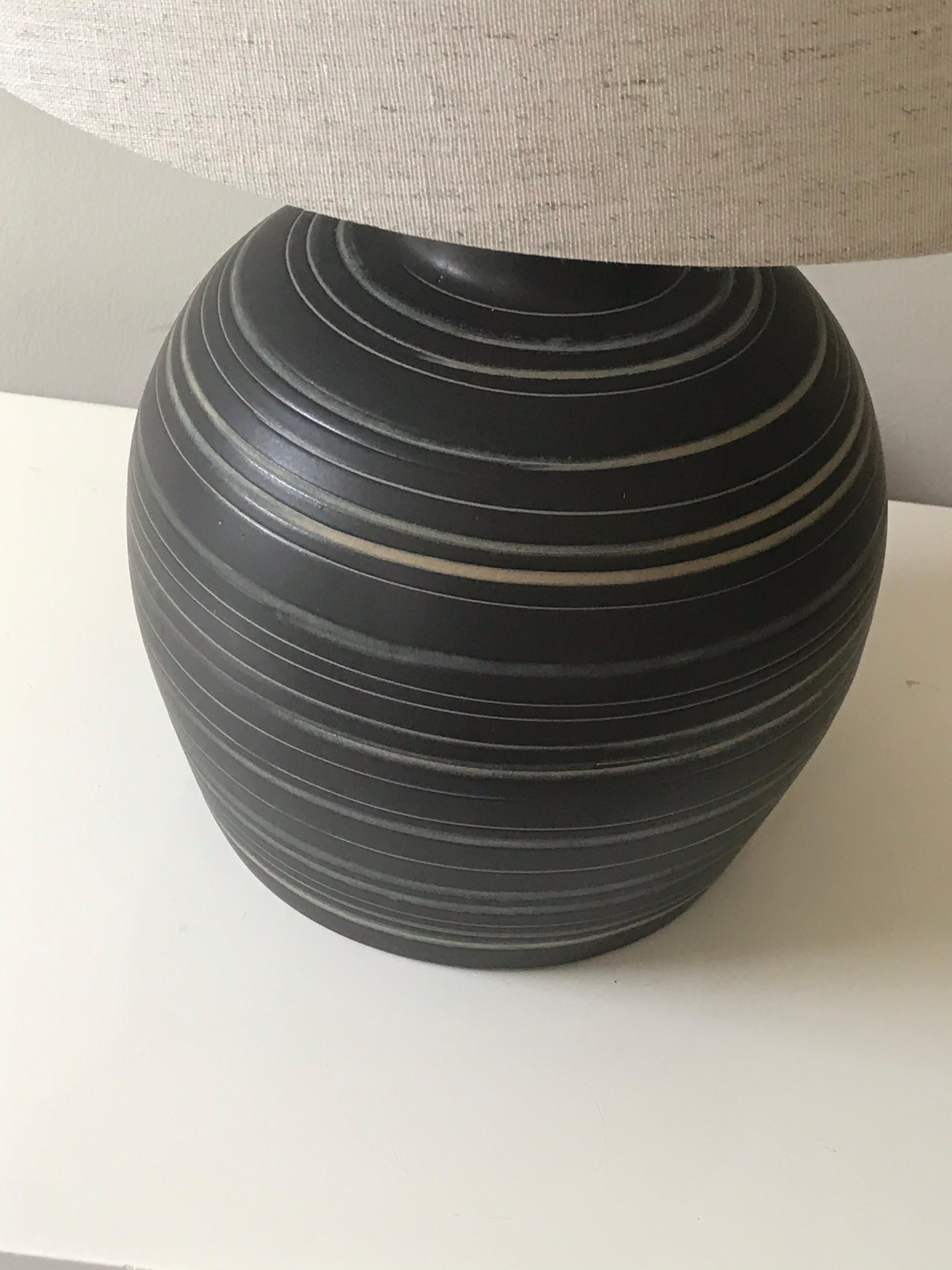 Elegant lamp by ceramicist duo Jane and Gordon Martz for Marshall Studios. Features an off black/ dark grey back with cream and light blue swirls. Newer wiring and new shade.

Overall- 
23.5