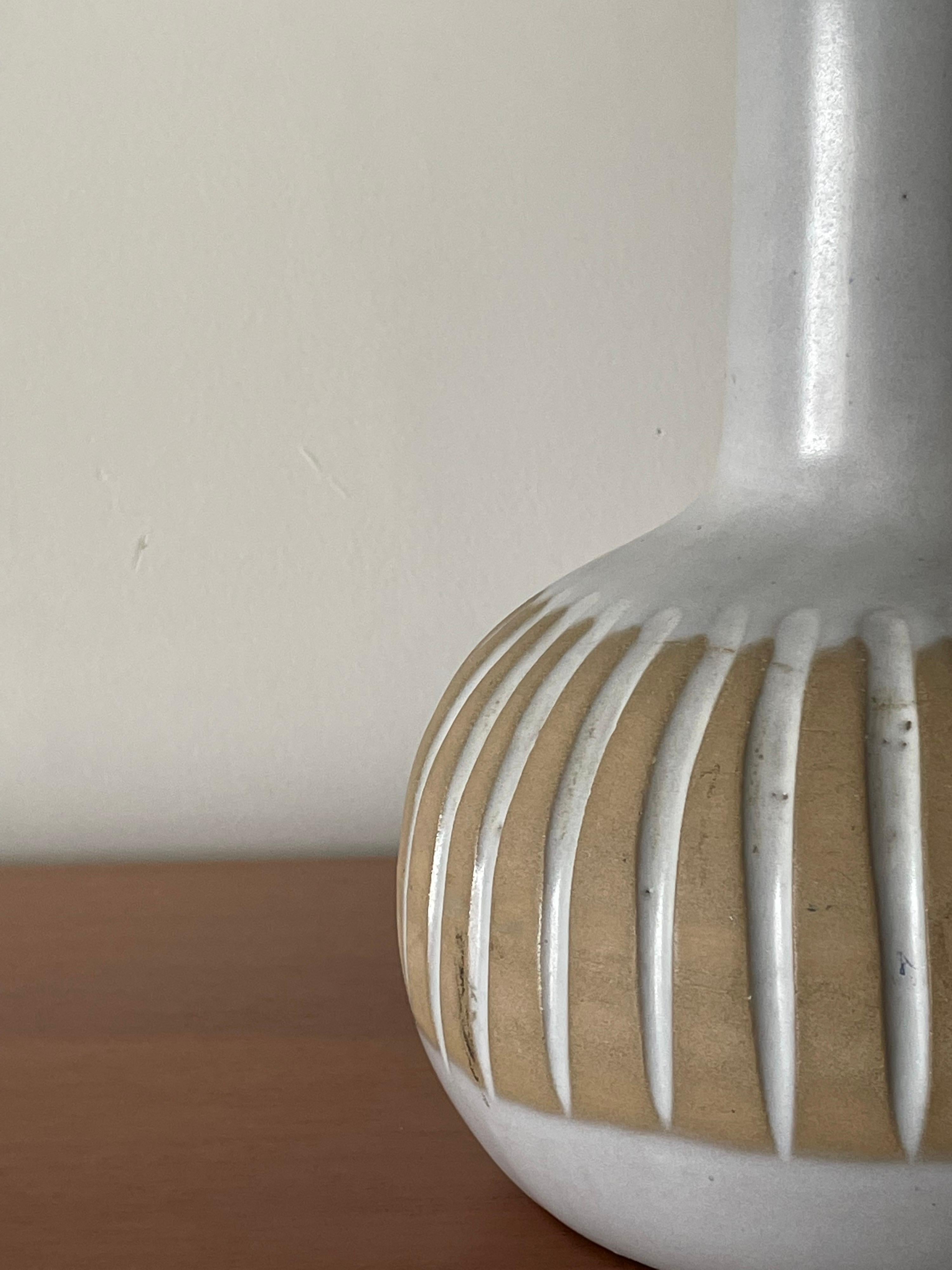 Lampe de table en céramique du célèbre duo de céramistes Jane et Gordon Martz pour Marshall Studios. Avec un corps en céramique et un embout en noyer. Les couleurs blanche et bisque se marient parfaitement dans de nombreux intérieurs.

En