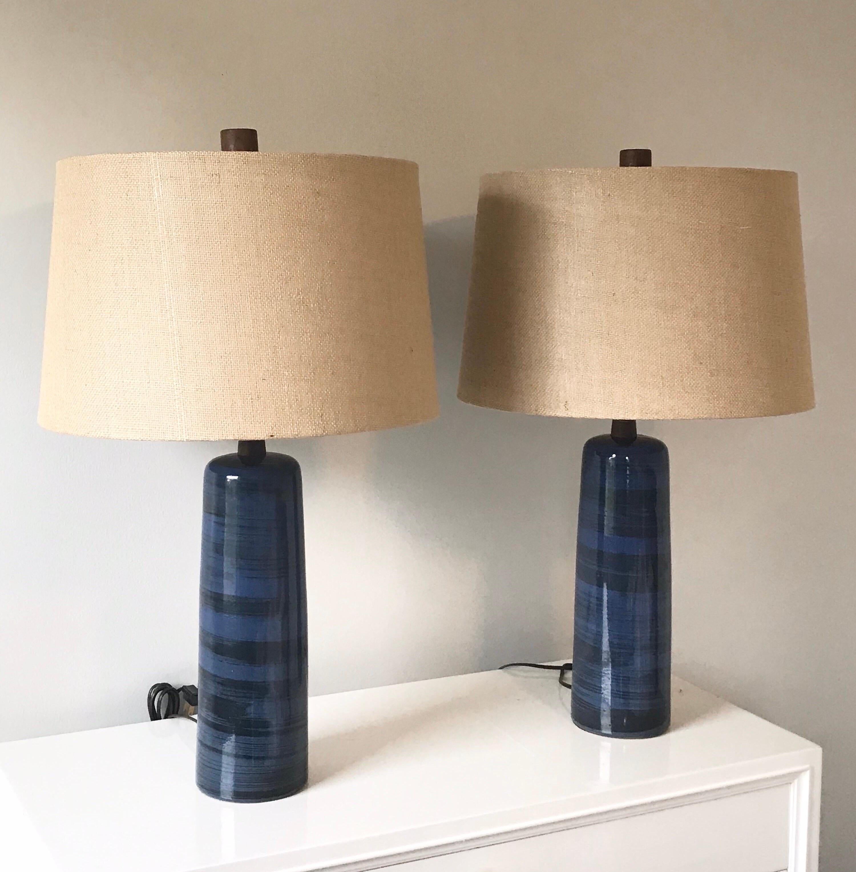 Stunning pair of lamps by Jane and Gordon Martz. Lamps feature a tall ceramic base in dark blue and black stripes/ swirls, a walnut neck, and complimented with a walnut finial. Lamps have new shades and wiring appears updated at some point with a
