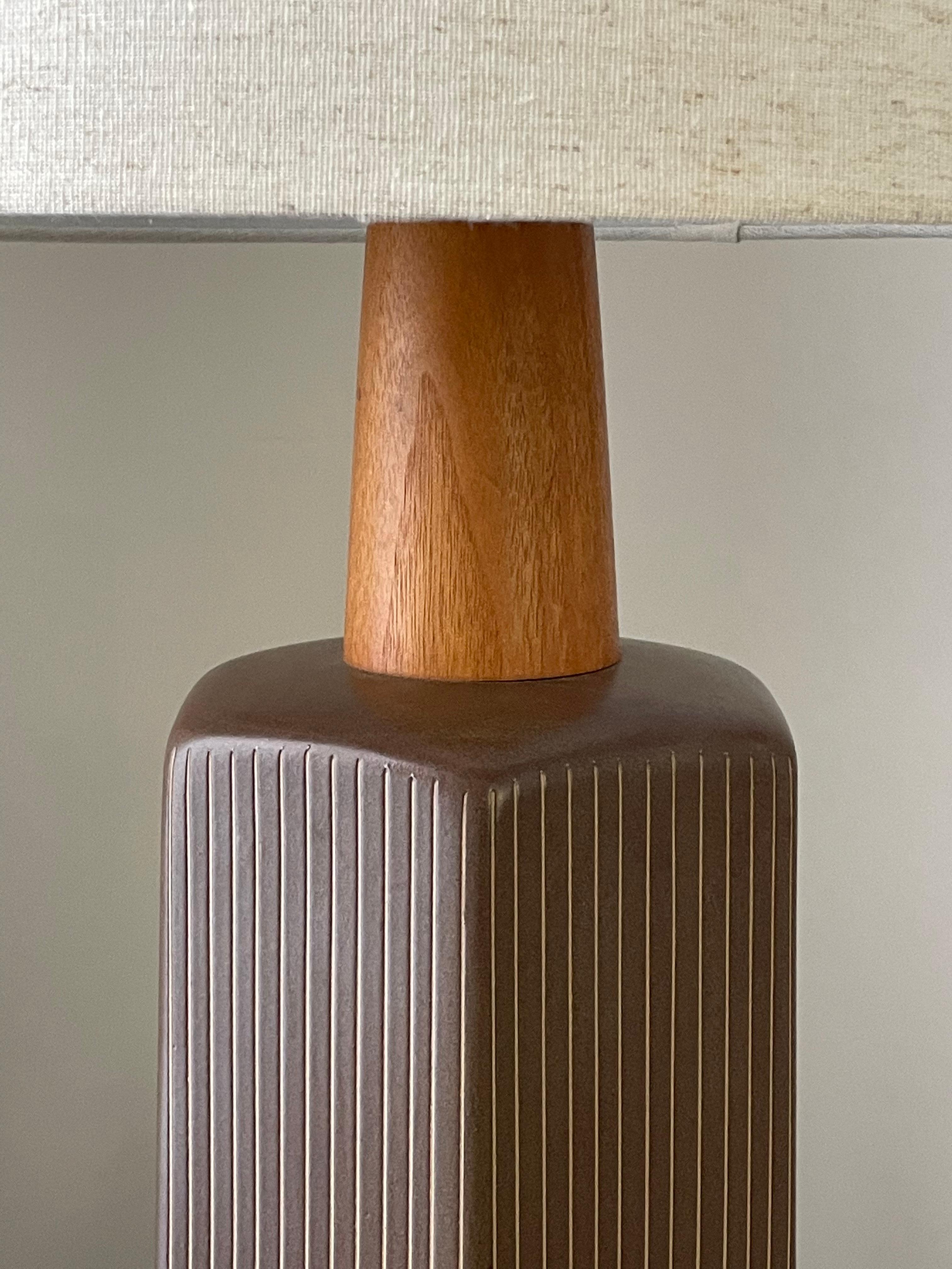 Merveilleuse lampe de table minimaliste en céramique réalisée par le célèbre duo de céramistes Jane et Gordon Martz pour Marshall Studios. La base hexagonale en céramique est accentuée par un épais col et un embout en noyer. La couleur est un brun