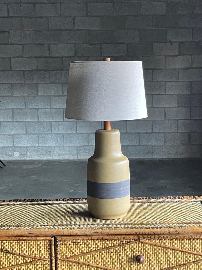 Large ceramic table lamp by famed ceramicist duo Jane and Gordon Martz for Marshall Studios. Features a well rounded yellowish body with a dark rough glazed band. Complete with a walnut neck and finial.

Measures: Overall
29” tall
15”