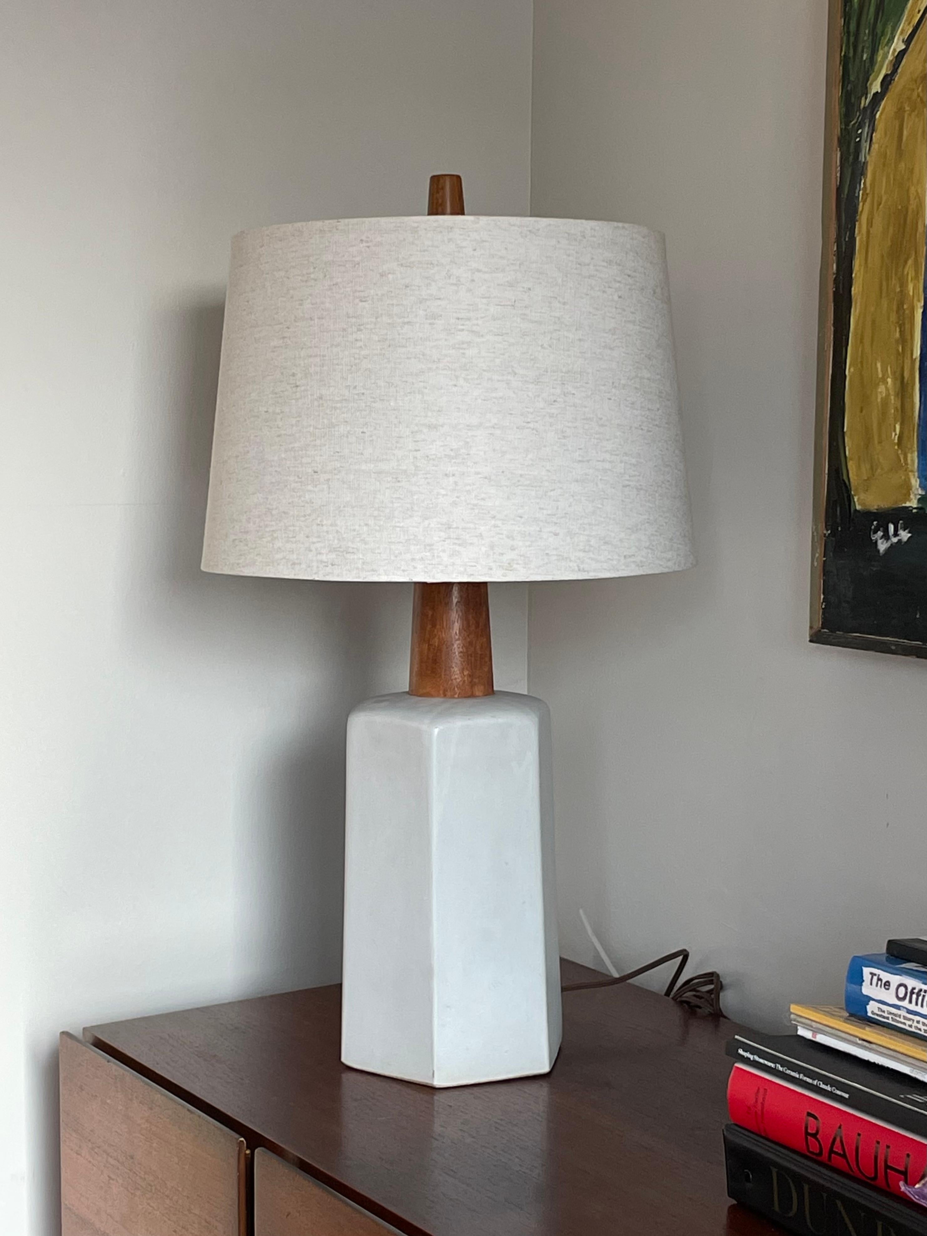 Wonderful minimalist table lamp in ceramic by famed ceramicist duo Jane and Gordon Martz for Marshall Studios. Features a ceramic hexagon base accentuated with a thick walnut neck and finial. Color is an off white which appears almost light grey in