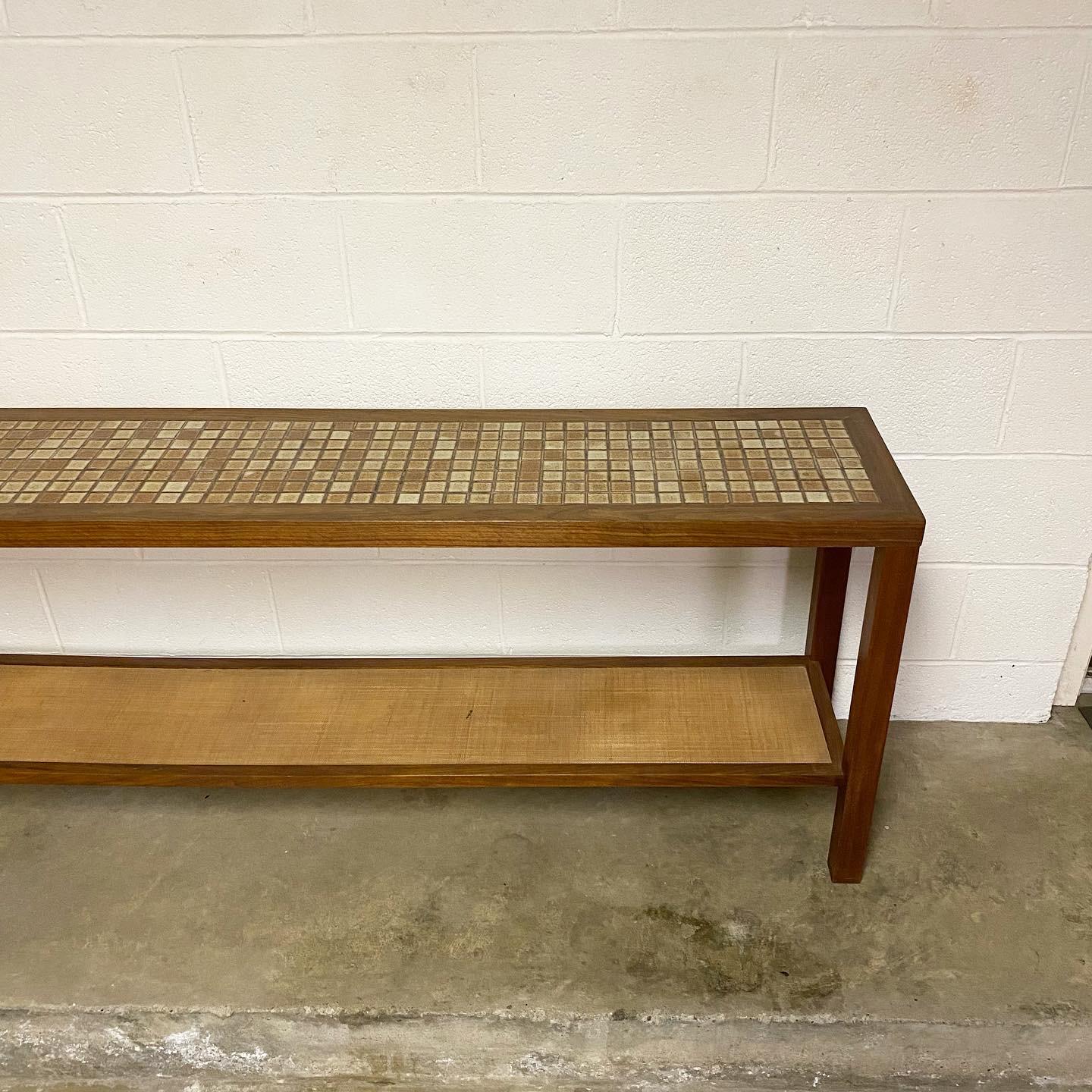This is an exceptionally rare sofa table designed by Jane and Gordon Martz for their company Marshall Studios, ca 1970's. The handmade and hand-laid tile along with the beautifully selected walnut work well with the cane bottom shelf. Even the