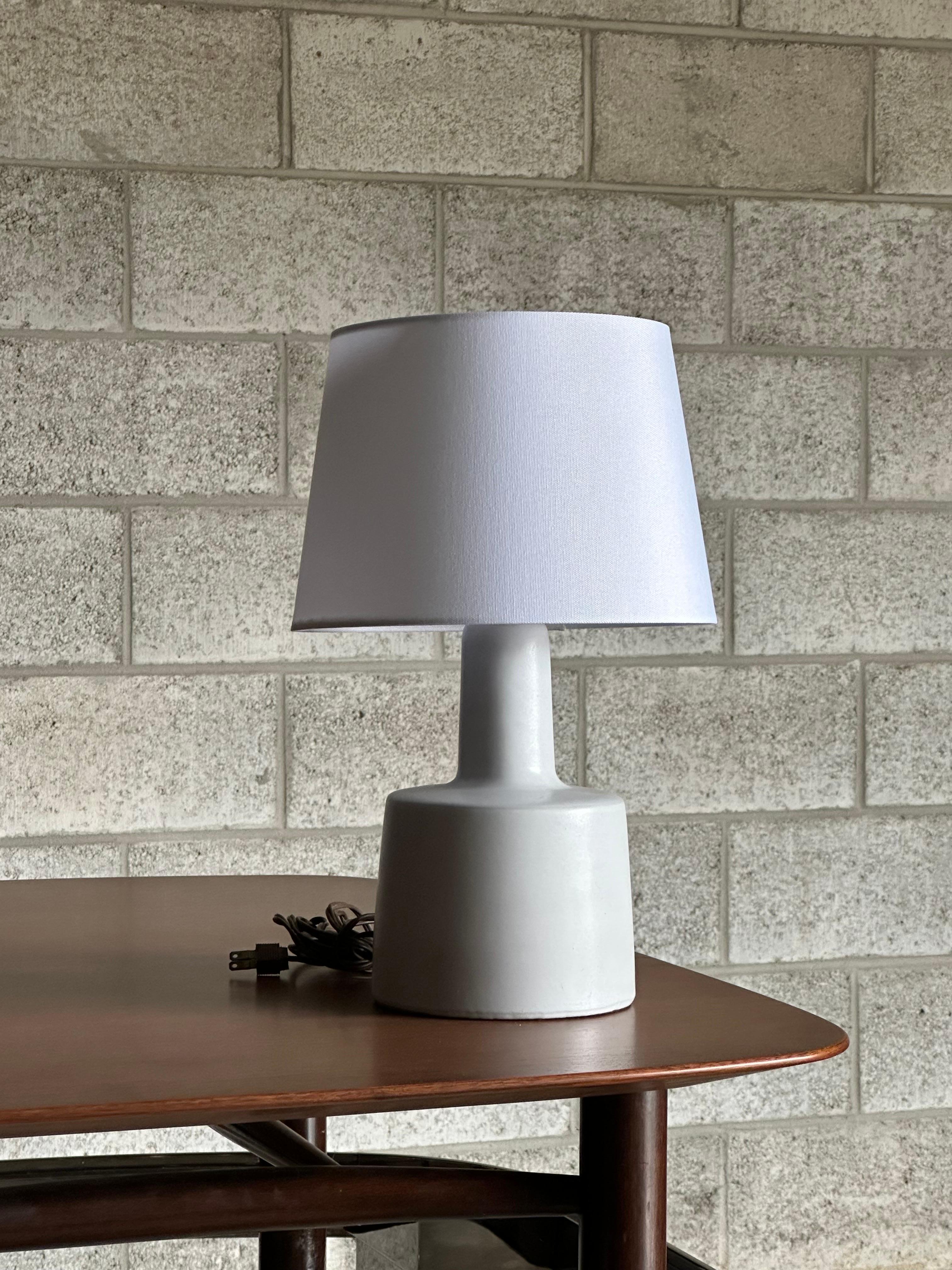 Lampe de table conçue par le duo de céramistes Jane et Gordon Martz pour Marshall Studios. La couleur est blanc cassé avec une glaçure plate. 

Dimensions générales : 
16
