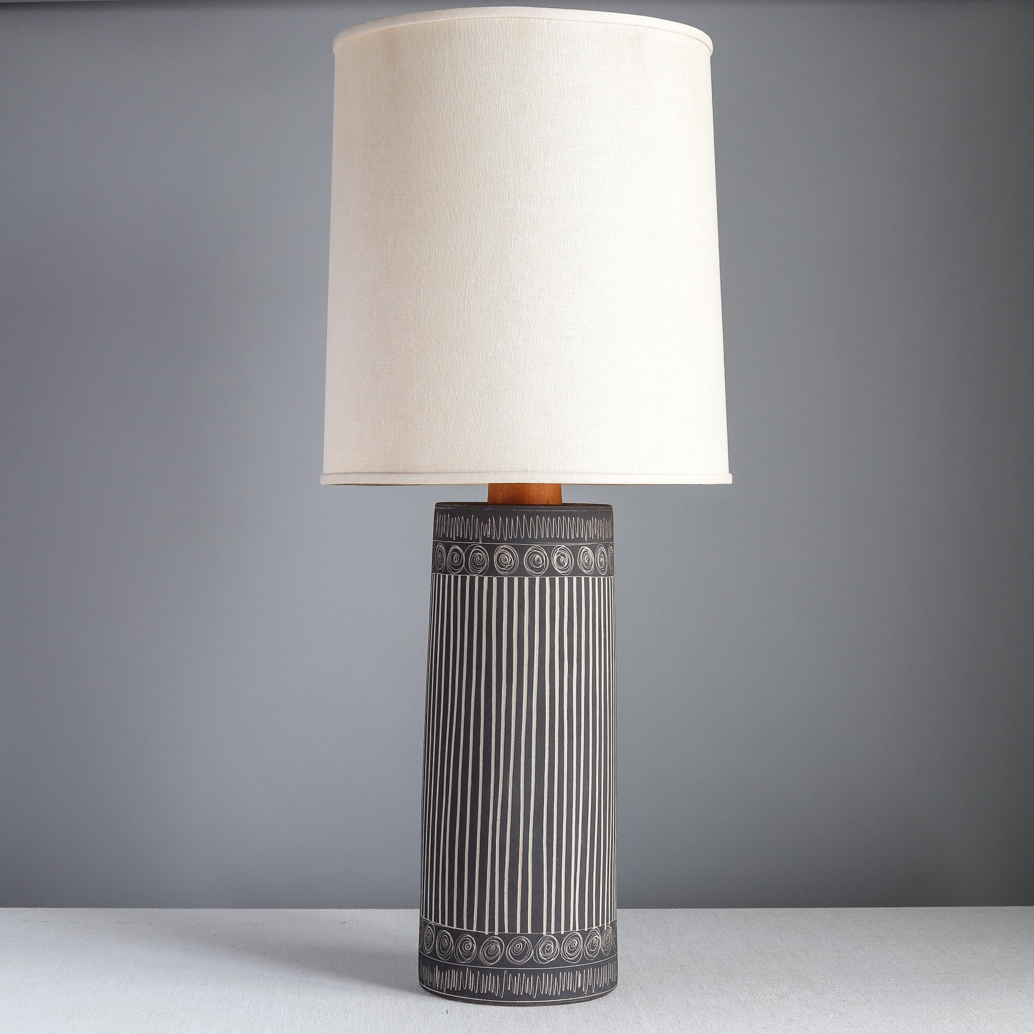 Mid-century ceramic table lamp designed by Jane and Gordon Martz for Marshall Studios of Veedersburg, Indiana. The stoneware body has a very matte dark gray glaze with hand-incised vertical lines and bands of round swirls. The neck of the lamp is