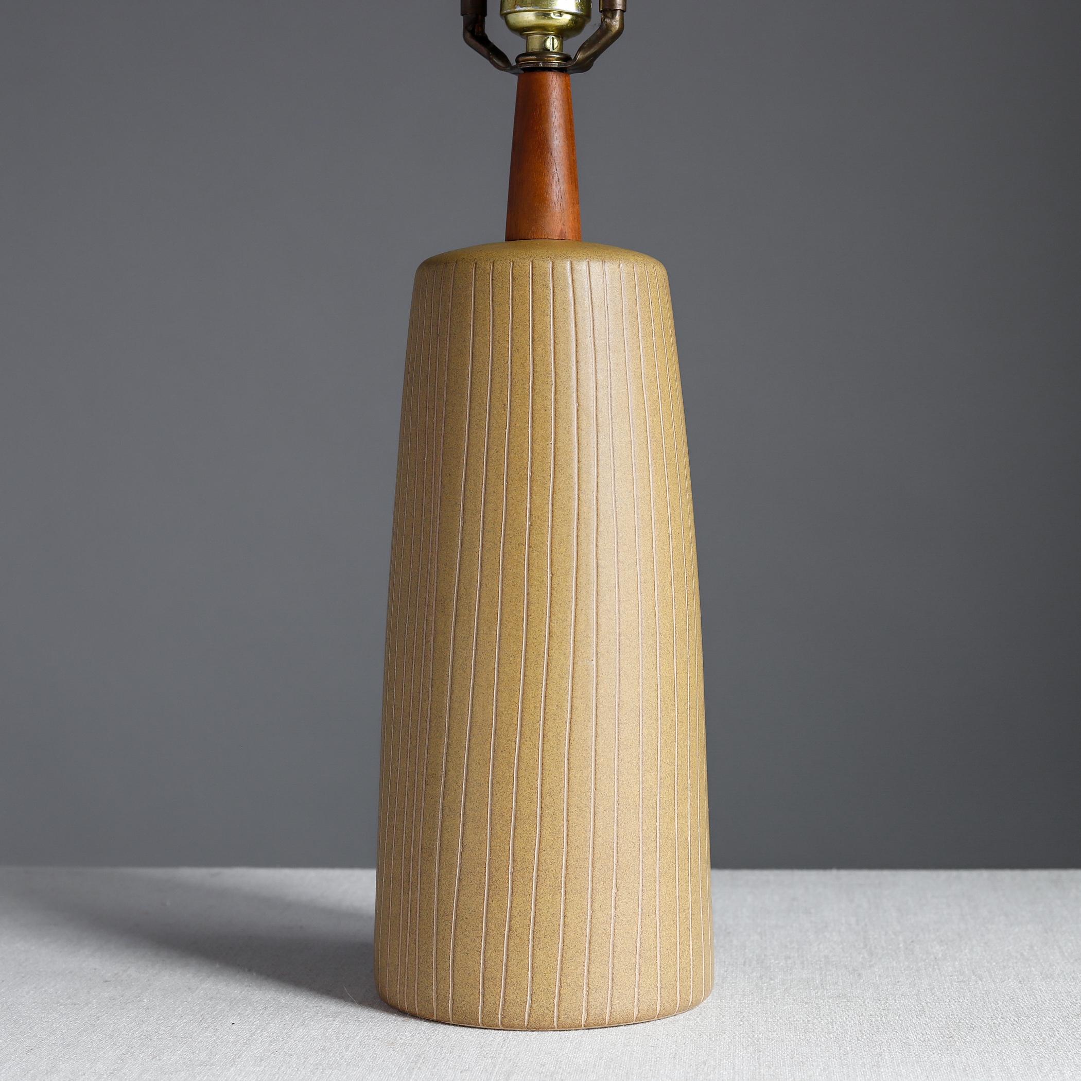 Midcentury ceramic table lamp designed by Jane and Gordon Martz for Marshall Studios of Indiana. The stoneware body has a warm mustard-y glaze with hand-incised vertical lines, mounted with a walnut neck and with original walnut finial. Signed