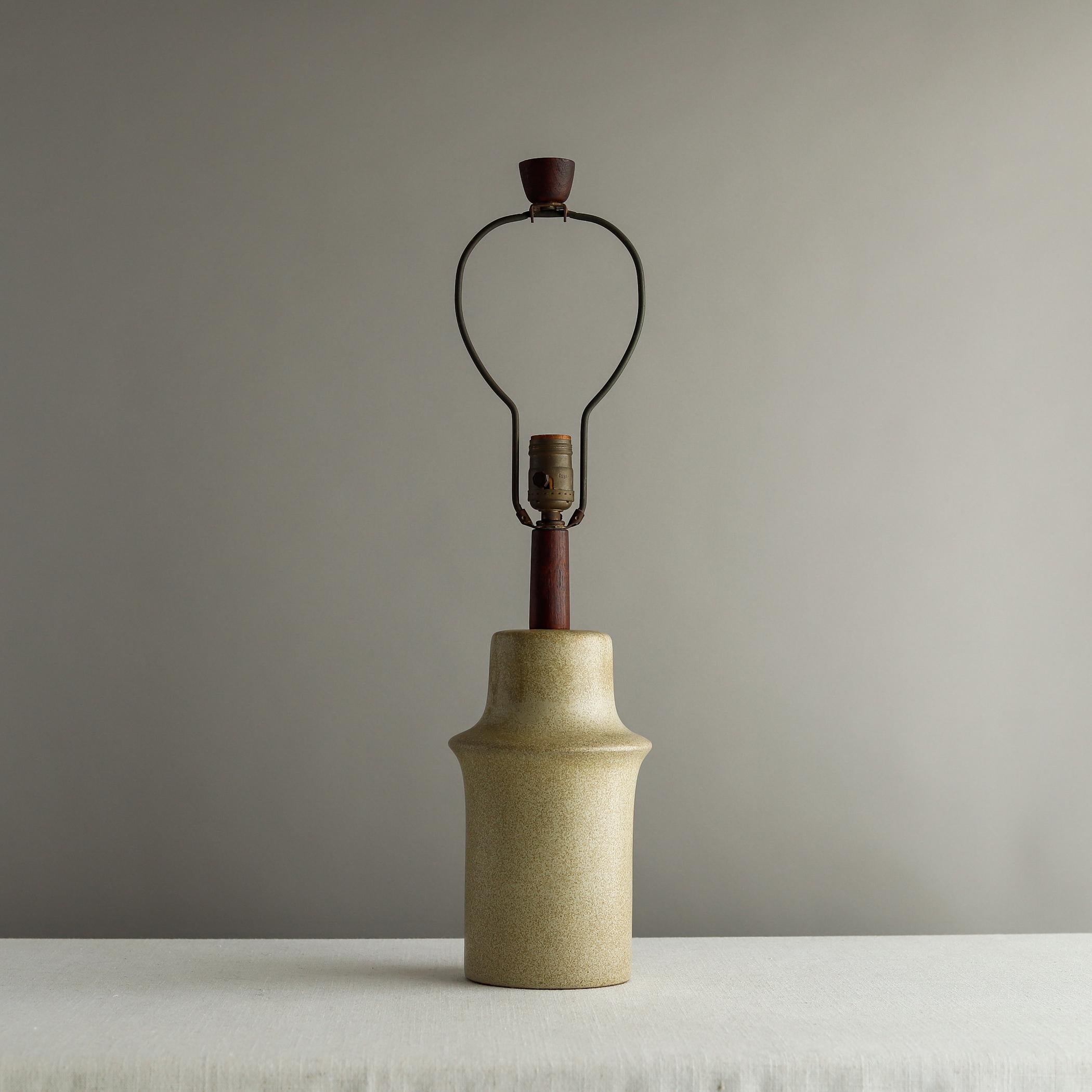Midcentury ceramic table lamp designed by Jane and Gordon Martz for Marshall Studios of Indiana. The stoneware body is molded with protruding band near the top and has a speckled neutral glaze, mounted with a walnut neck and with original walnut
