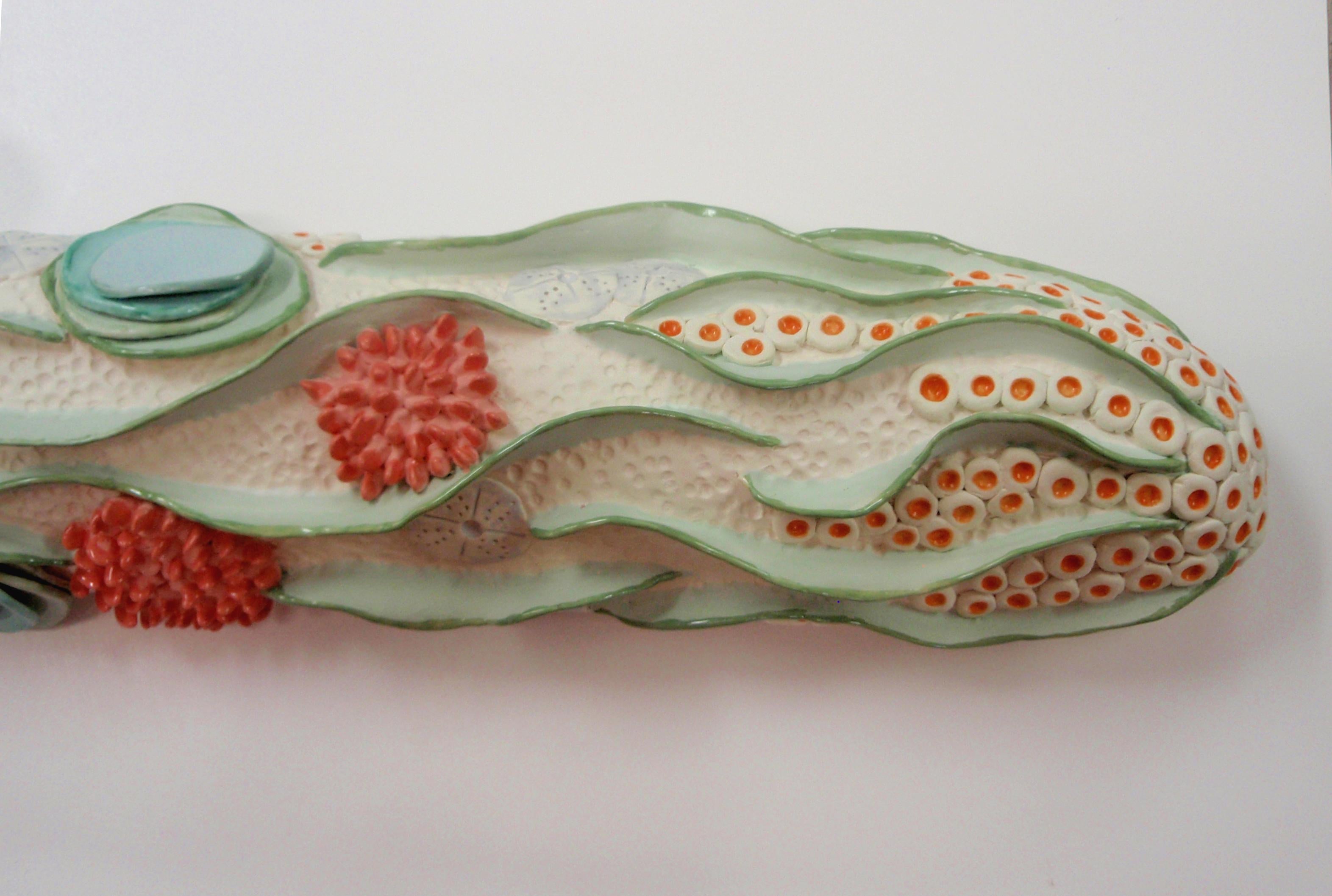 Oceanic themed coral reef inspired ceramic sculpture hanging wall piece that is, clean, minimal, white with green, coral pink, pale blue and orange. The work is created in three parts that each hang from an attached wire on a nail or hook. The three