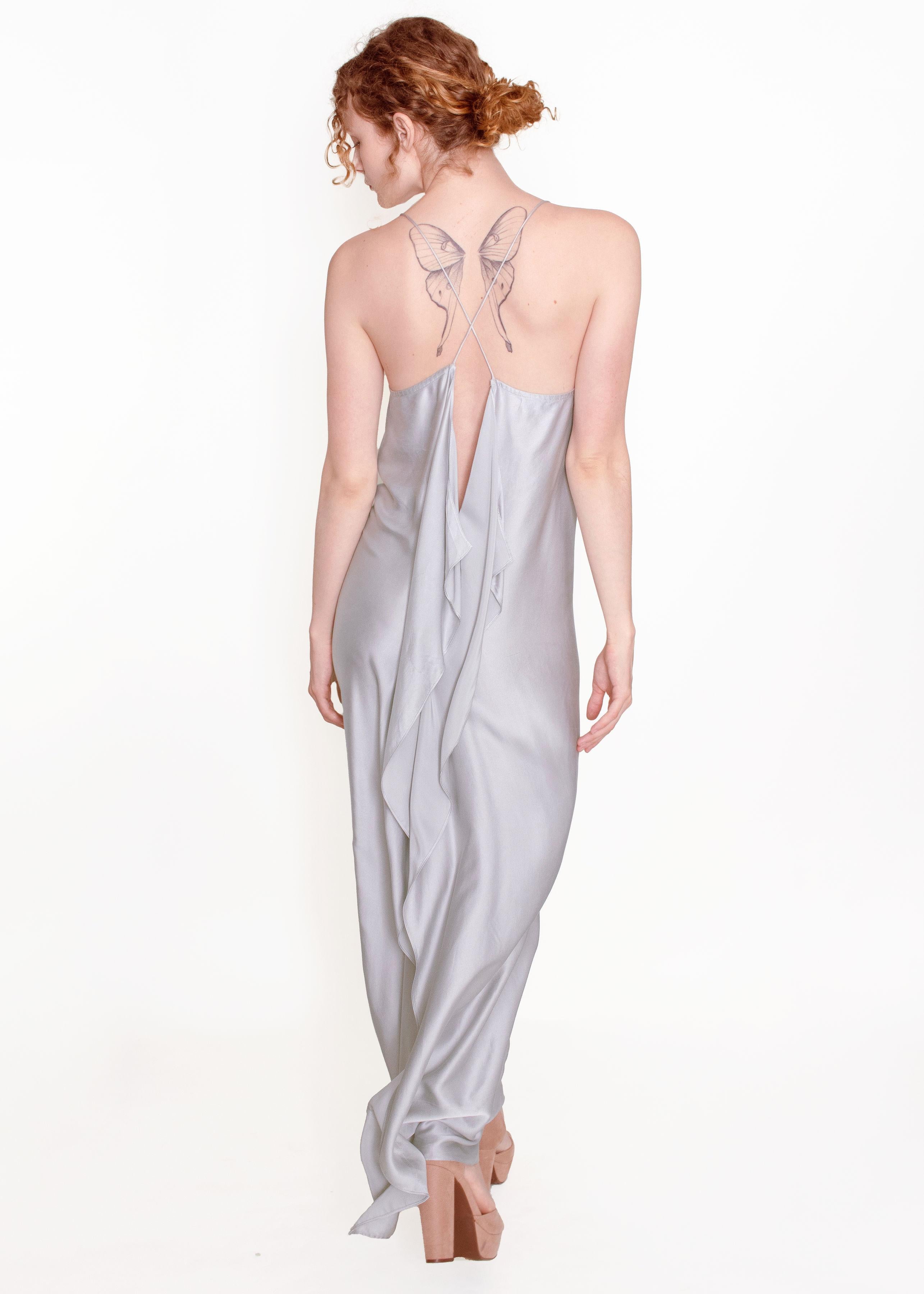 This Jane Booke Silver Cross Back Silver Slip Dress is an stunning and unique piece! It is made of 100% silk in a beautiful silver color with a very high slit down the back that cuts in the right place.  Cut on the bias for a flattering silhouette,