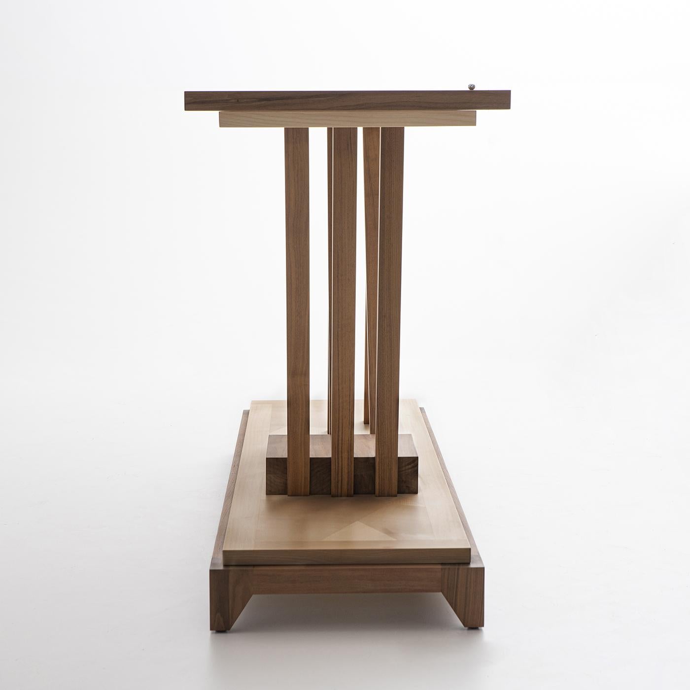 The sleek lines of this console table in walnut and maple are a contemporary take on tree branches and their organic shapes. The lower sculptural ensemble of crossing and interrupted elements serves as the suport for the rectangular top. The top