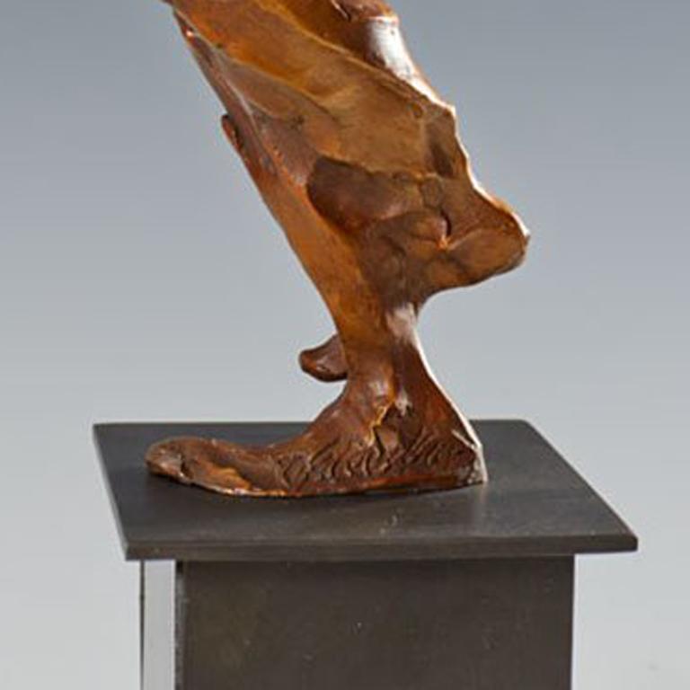 Sculpture of a woman with her arms raised in front of her and with one leg crossed over the other. 