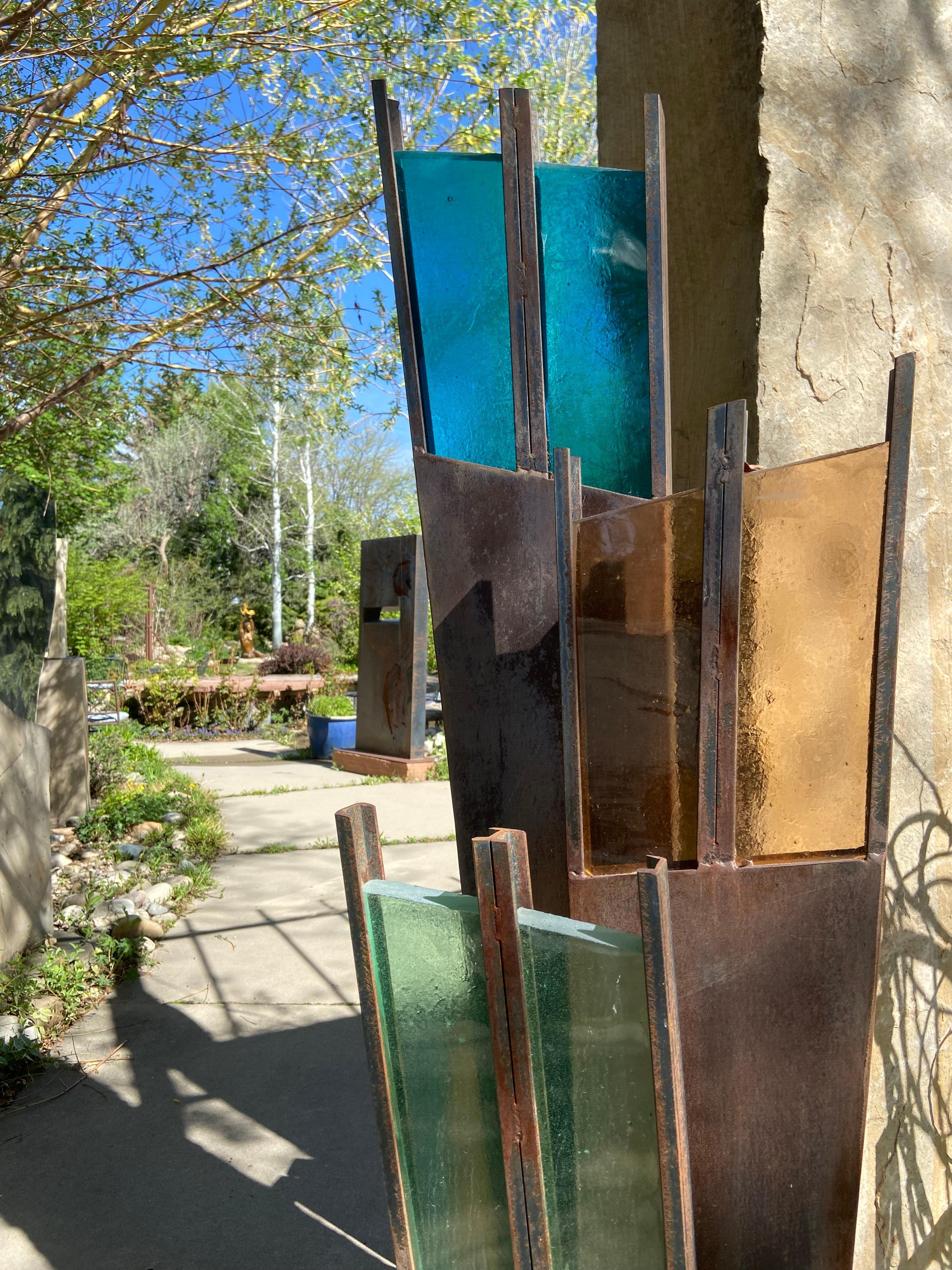 Unfolding by Jane DeDecker
Abstract Steel with Architectural Grade Glass. 
A large fan-like form that silhouettes beautifully in a garden, with jewel tone colored glass in green, orange and blue.
6ft tall one-of-a-kind

ABOUT THE ARTIST: 'Part of