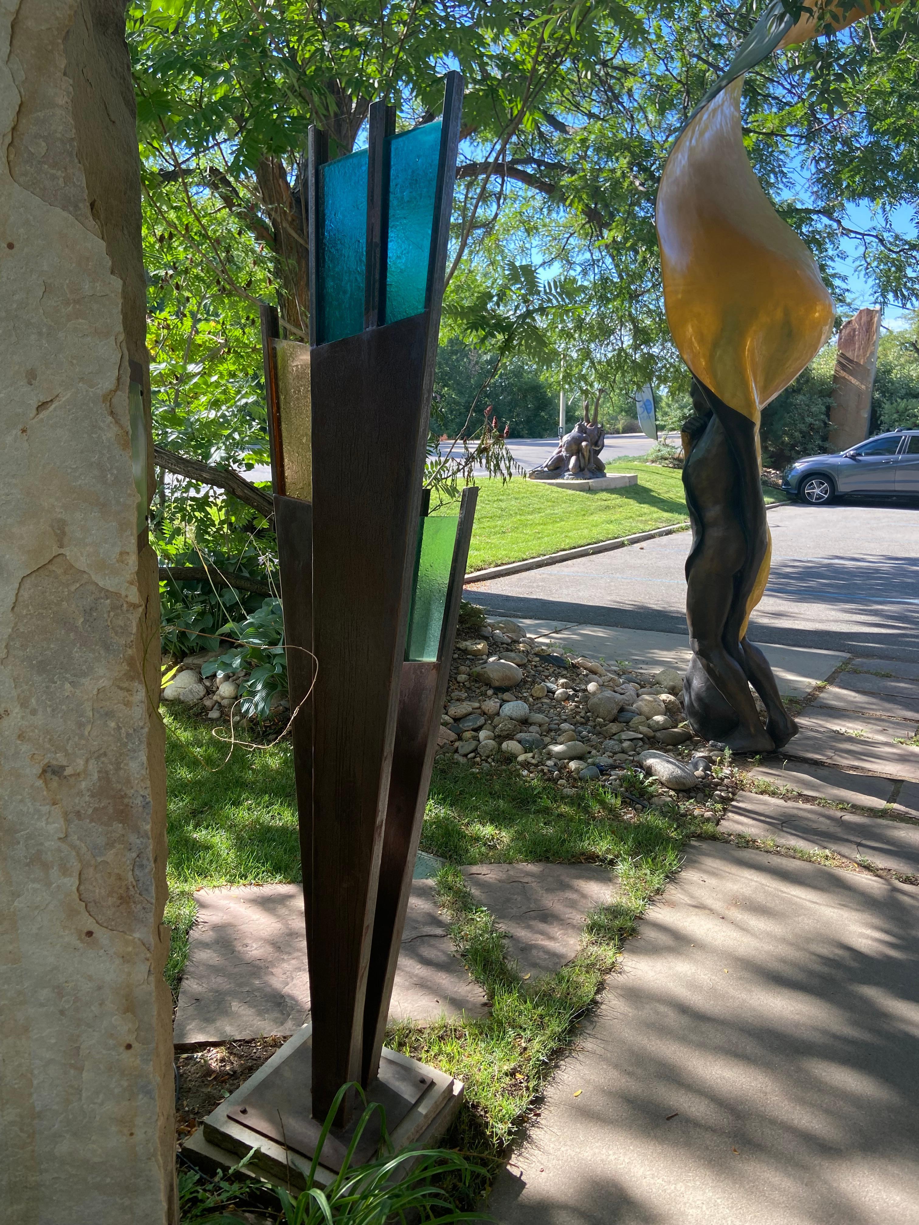 Desdoblamiento de Jane DeDecker
Acero Abstracto con Cristal de Calidad Arquitectónica. 
Una gran forma de abanico que se siluetea bellamente en un jardín, con cristales de color joya en verde, naranja y azul.
1,80 m de altura único en su