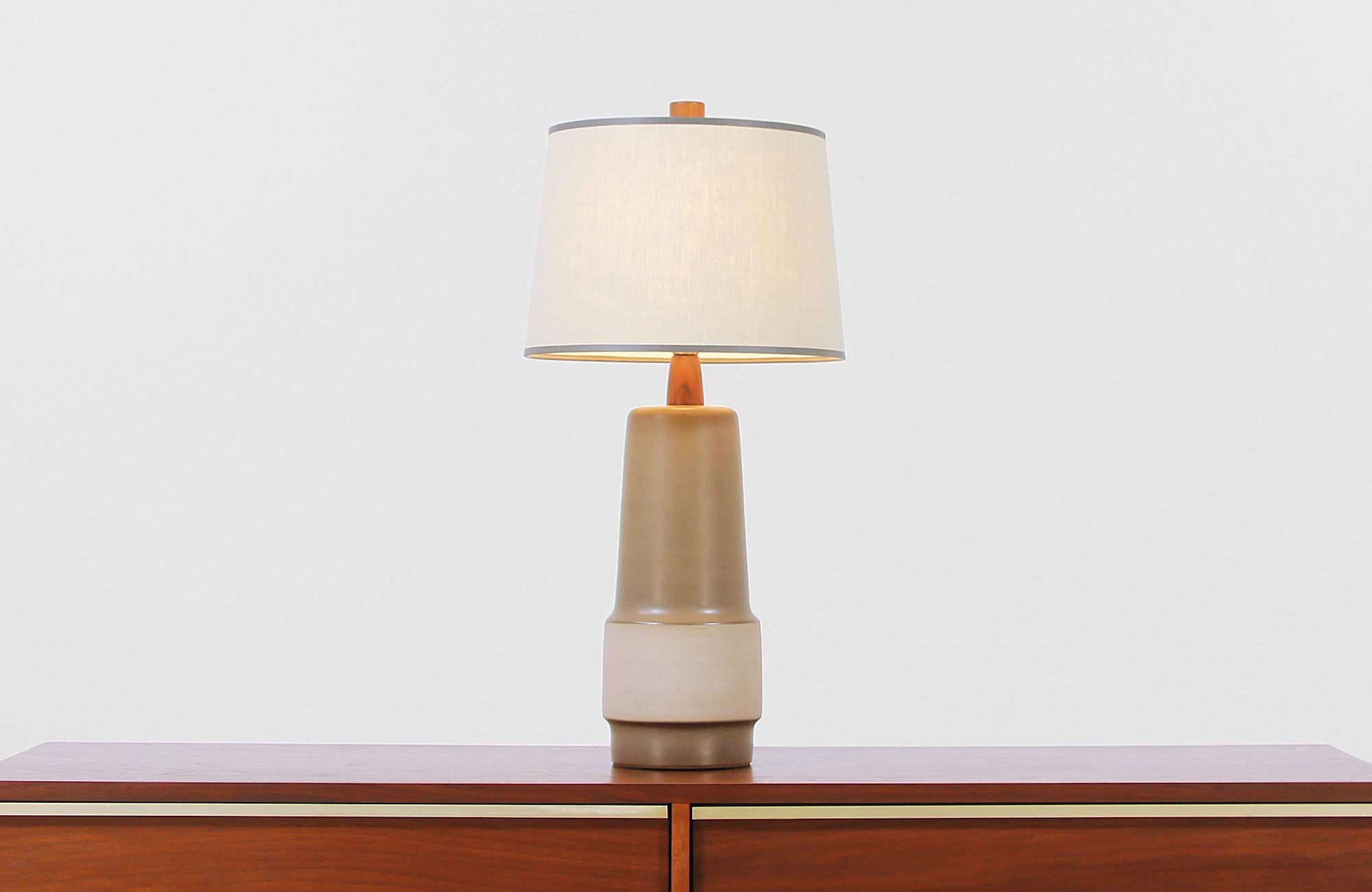 Mid-Century Modern ceramic table lamp designed by Jane & Gordon Martz for Marshall Studios in the United States, circa 1960s. This tall and elegant table lamp features a two-toned glazed ceramic body with walnut wood details creating a contrast of