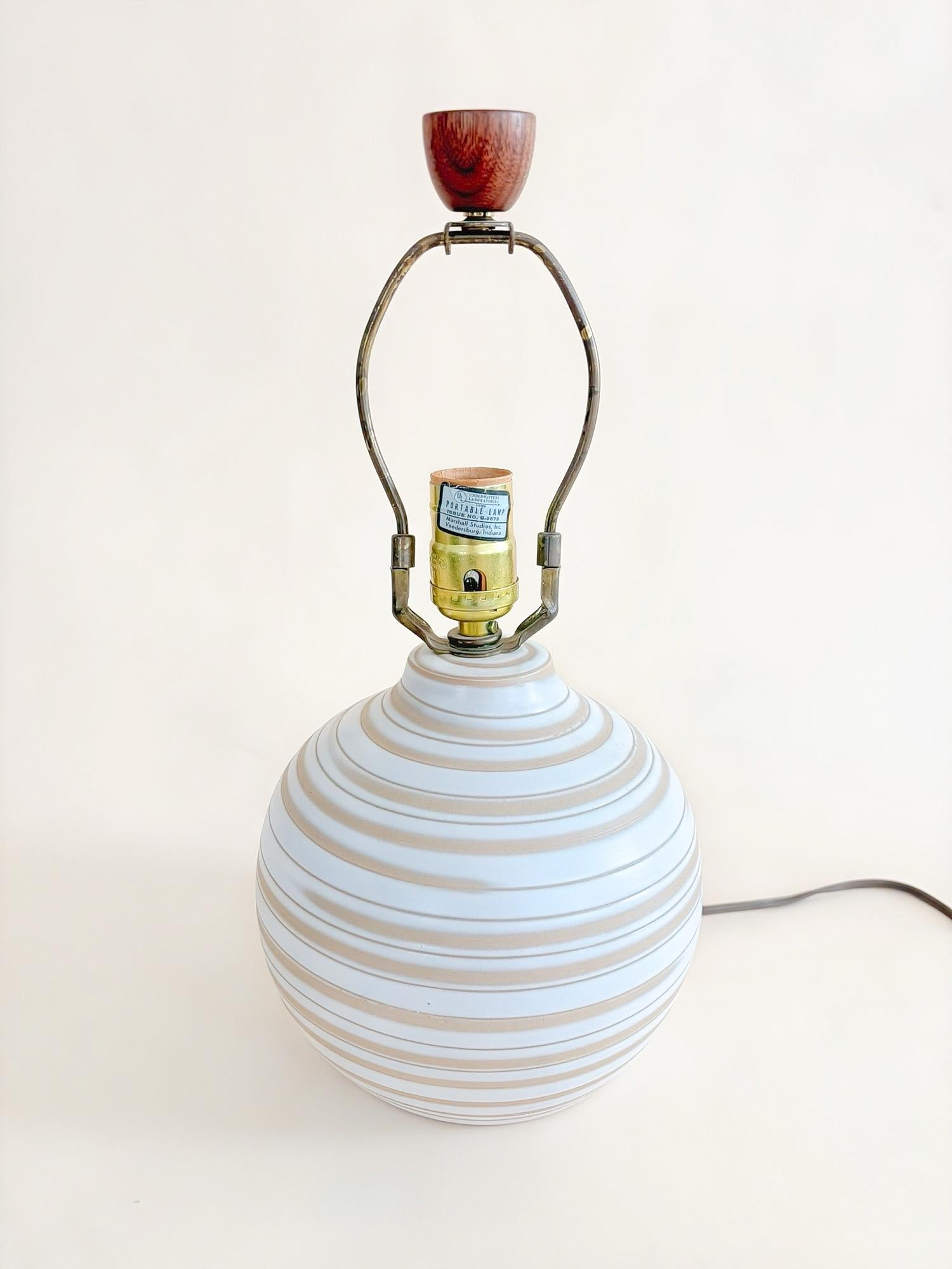 Eine fein gearbeitete, cremefarbene und glasierte Keramik-Tischlampe, die von dem berühmten Ehepaar Jane und Gordon Martz entworfen und von Marshall Studios in den 1960er Jahren hergestellt wurde. Der zylindrische Keramikkörper zeichnet sich durch
