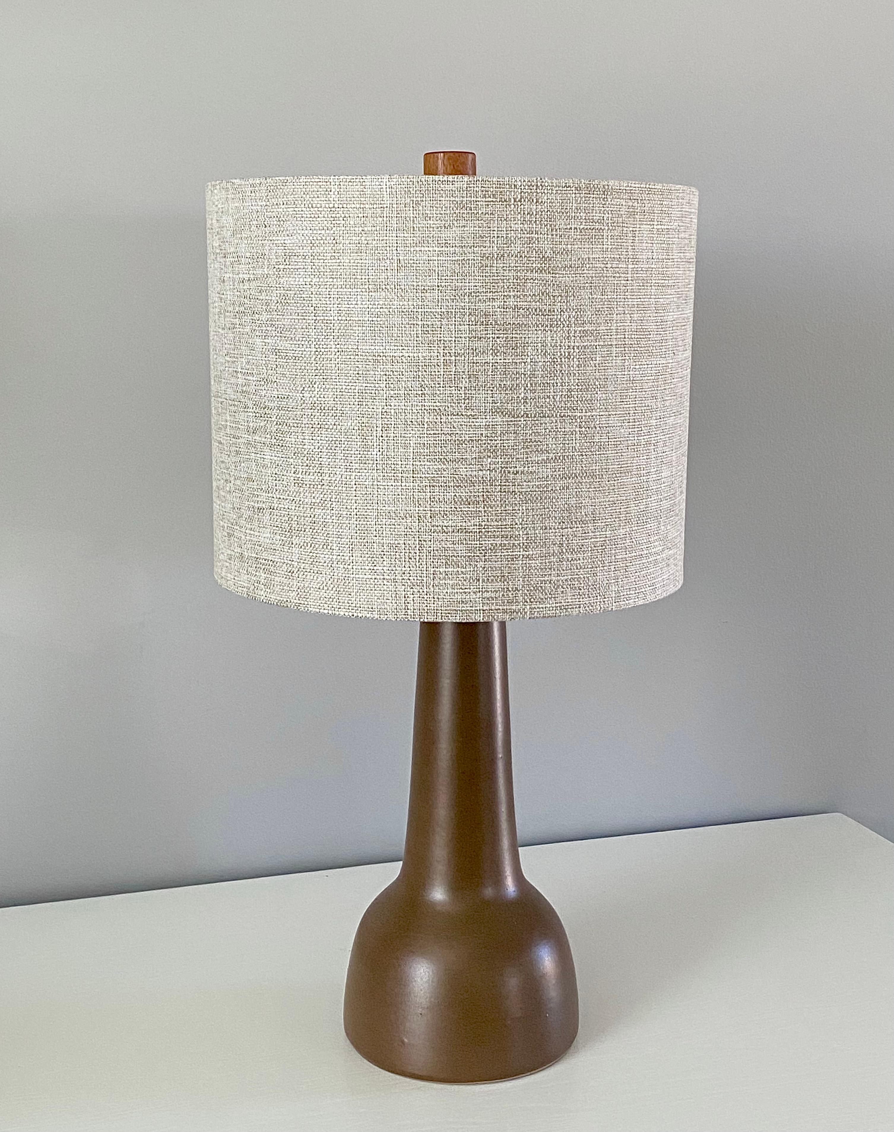 This minimalist organic table lamp is designed by the famed husband and wife duo, Jane & Gordon Martz. The color is a speckled earth tone brown with a lovely delicate aged patina. The base is signed and in excellent condition. The lamp is sold