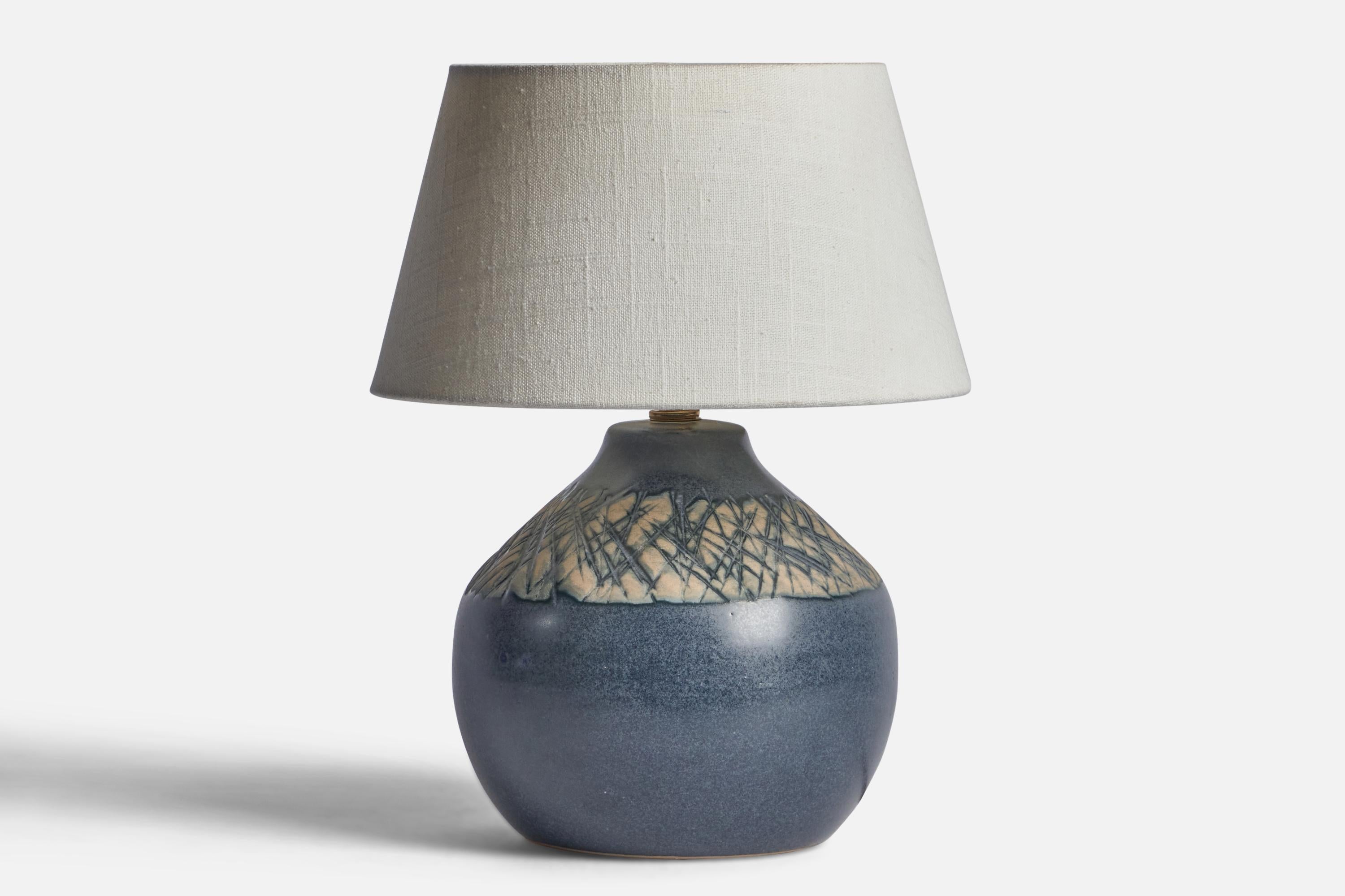 A beige and blue-glazed ceramic table lamp designed by Jane & Gordon Martz and produced by Marshall Studios, USA, 1960s.

Dimensions of Lamp (inches): 10” H x 7.4” Diameter
Dimensions of Shade (inches): 7” Top Diameter x 10” Bottom Diameter x 5.5” H