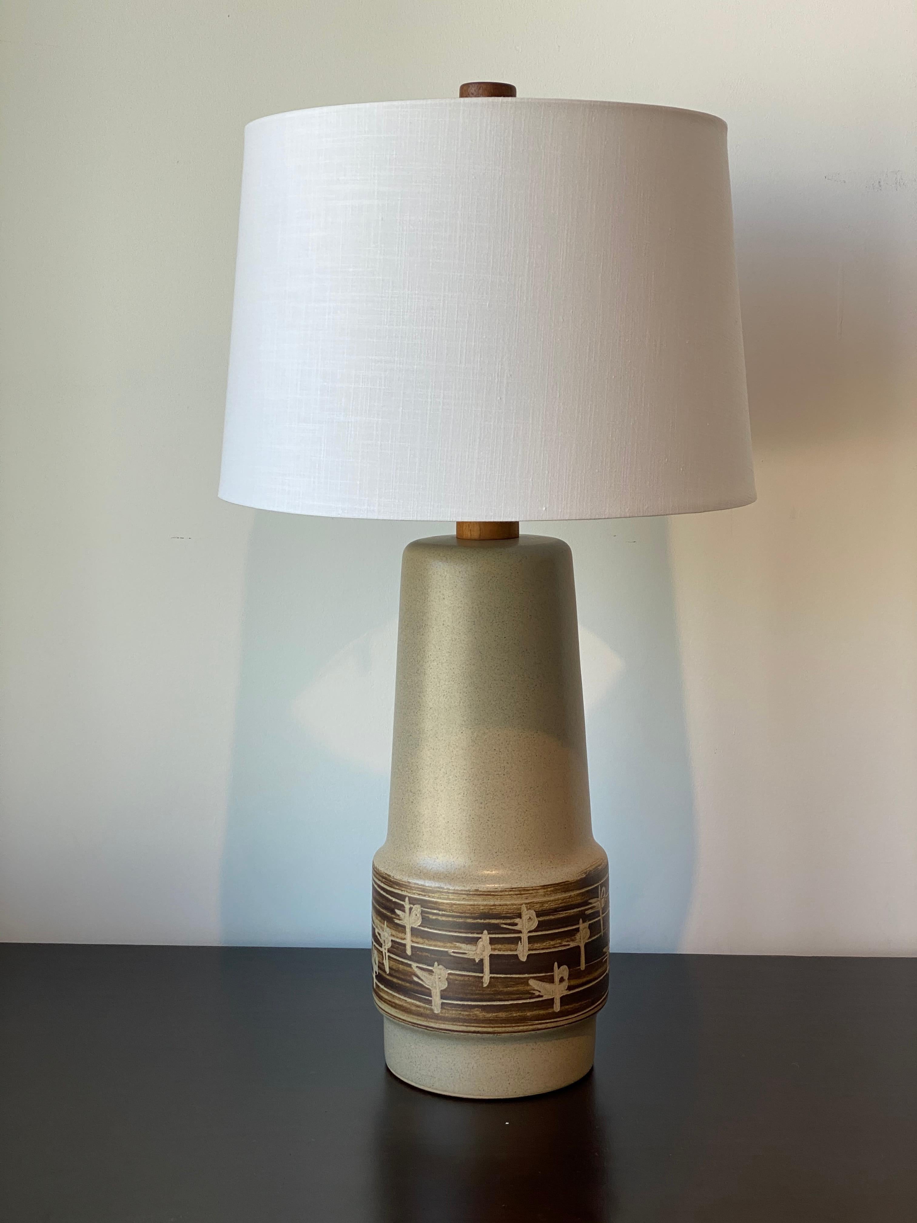 A beige and green ceramic and walnut table lamp designed by husband and wife duo Jane & Gordon Martz. Produced by Marshall Studios, Indianapolis. 

Bases are slip-cast and then dipped into glaze and hand painted. Design also incorporates exquisite