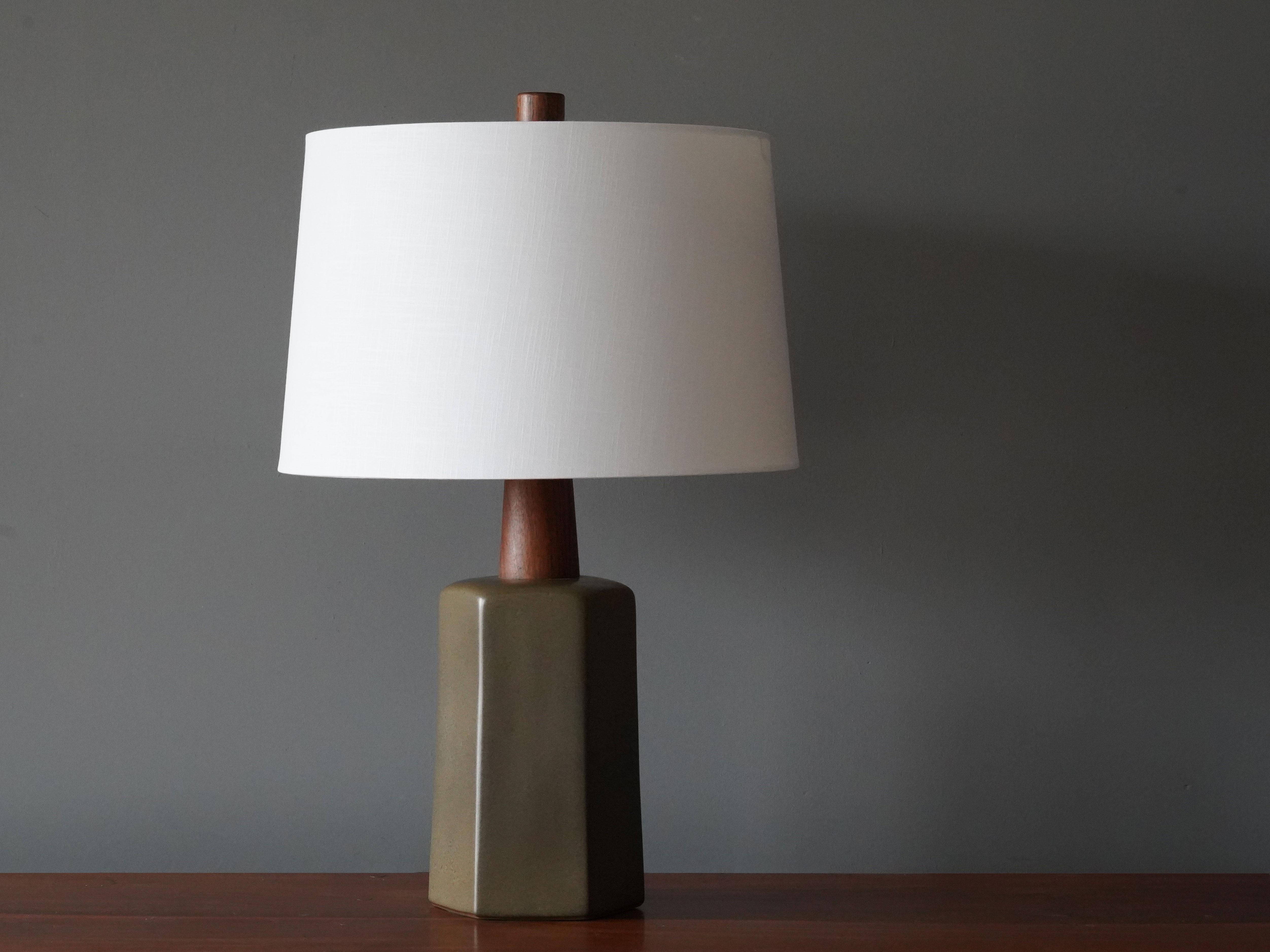 A table lamp designed by husband and wife duo Jane & Gordon Martz. Produced by Marshall Studios, Indianapolis. 

The olive green base is slip-cast and then dipped into glaze. Design also incorporates exquisite walnut neck and finial. Base is signed.