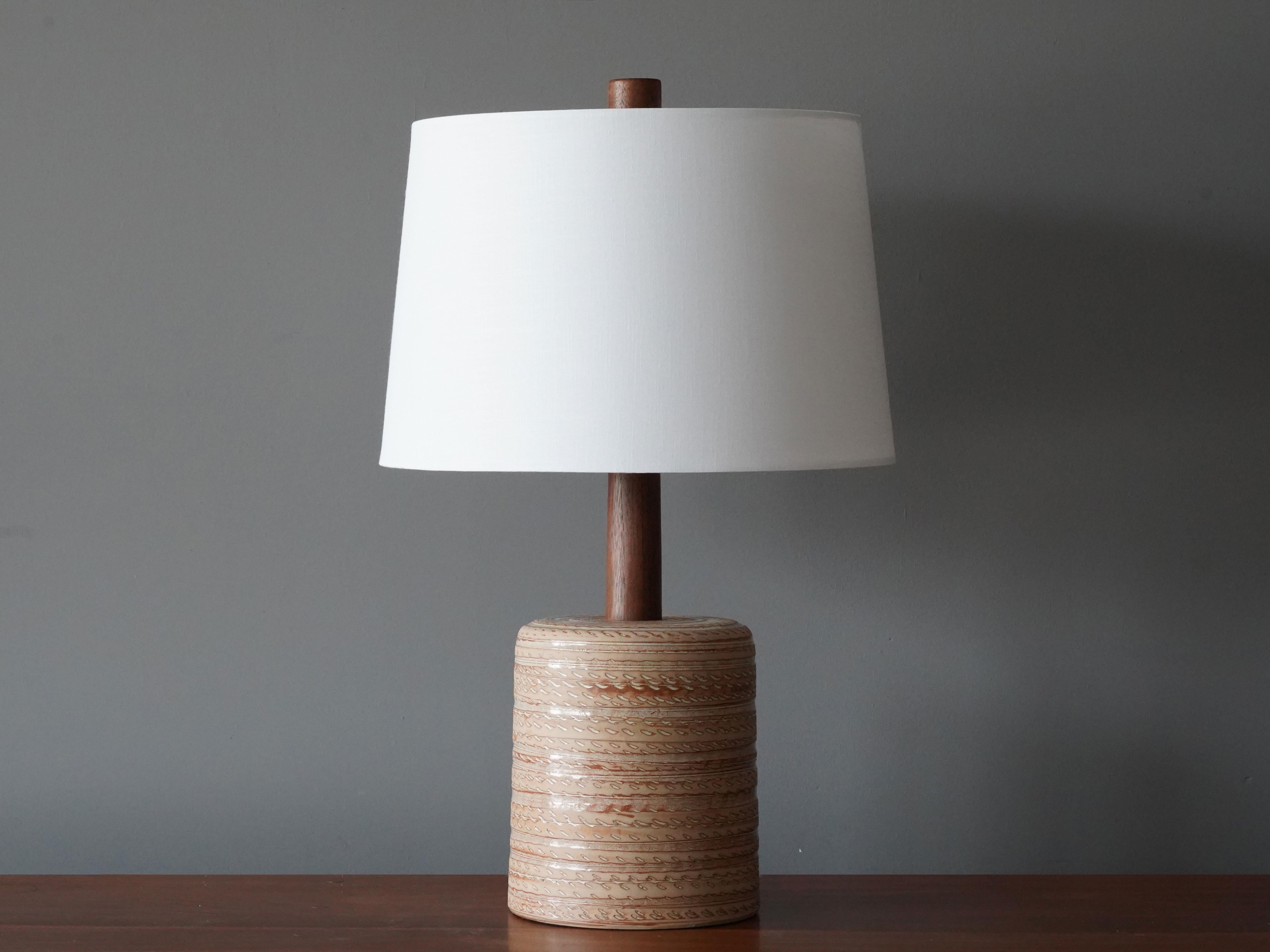 A table lamp designed by husband and wife duo Jane & Gordon Martz. Produced by Marshall Studios, Indianapolis. 

The base is slip-cast and then dipped into glaze and hand painted. Design also incorporates exquisite walnut neck and finial. Base is