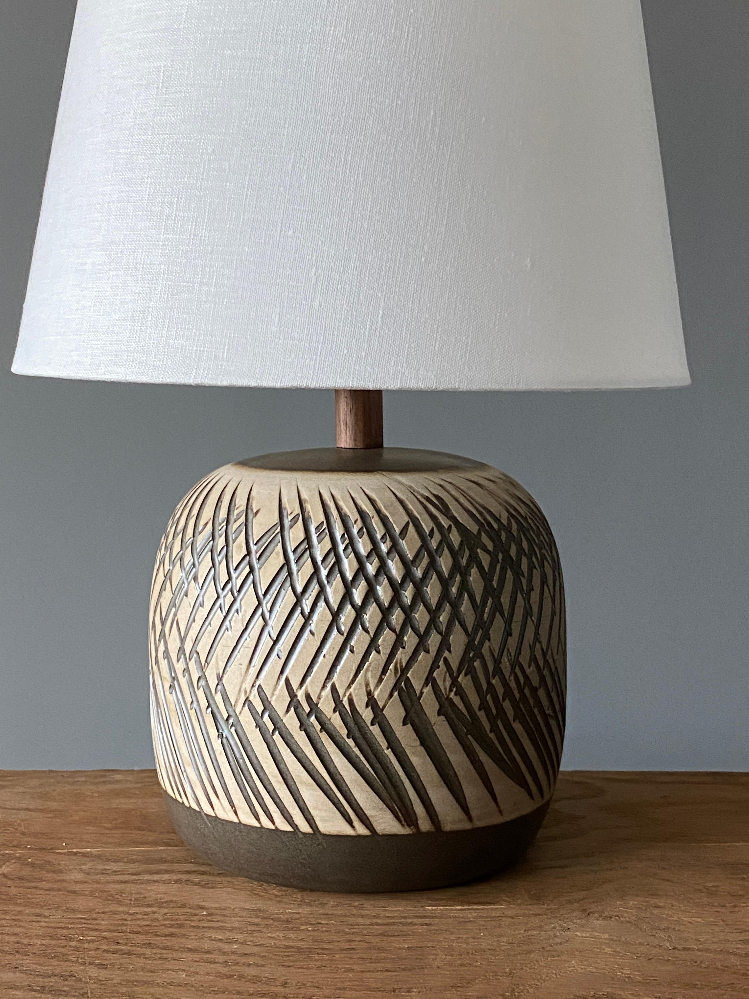A table lamp designed by husband and wife duo Jane & Gordon Martz. Produced by Marshall Studios, Indianapolis. 

The base is slip-cast and then dipped into glaze and hand painted. Design also incorporates exquisite walnut neck and finial. Base is