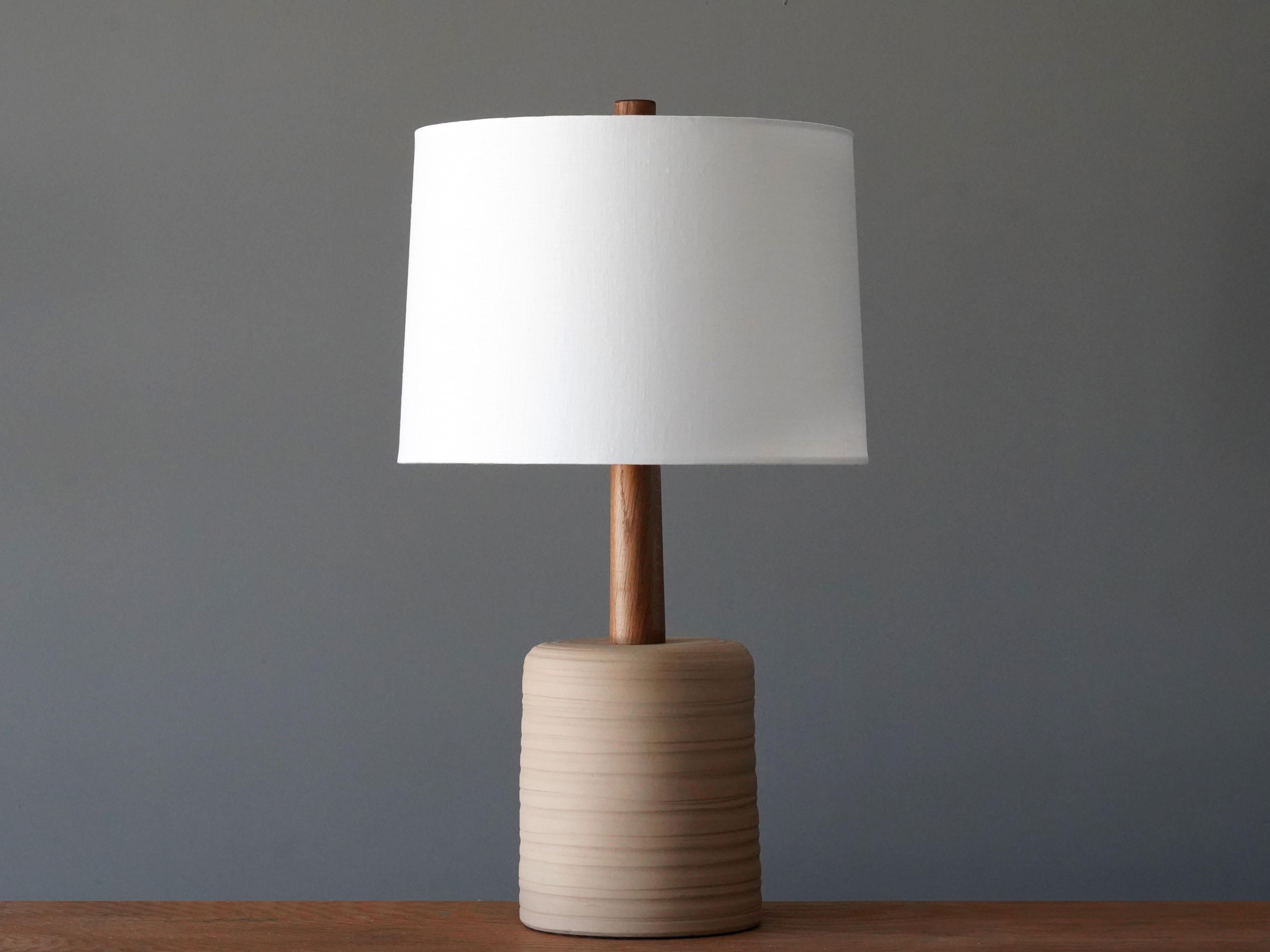 A table lamp designed by husband and wife duo Jane & Gordon Martz. Produced by Marshall Studios, Indianapolis. 

The base is slip-cast and then dipped into glaze and hand painted. Design also incorporates exquisite walnut neck and finial. Base is