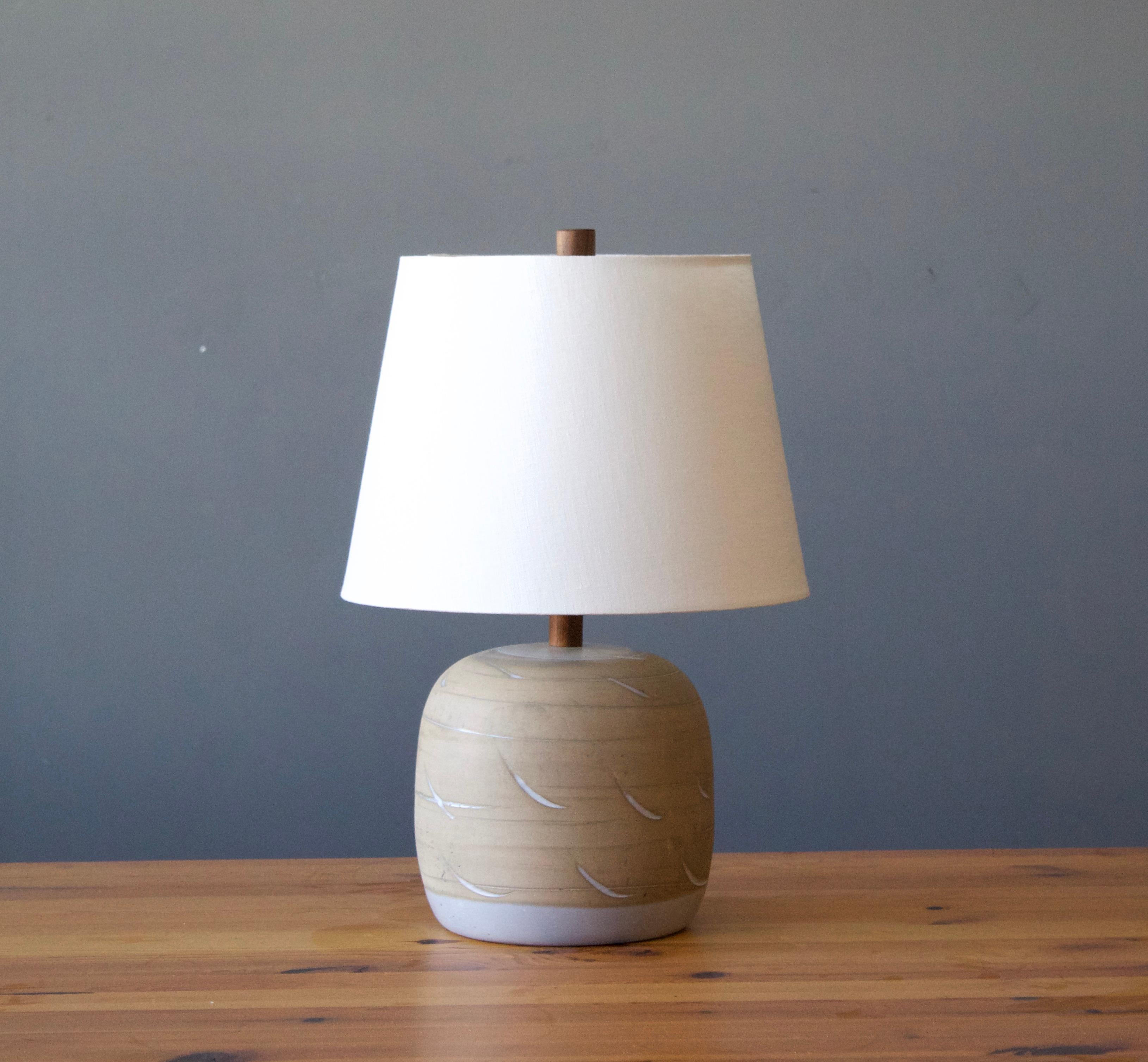 A table lamp designed by husband and wife duo Jane & Gordon Martz. Produced by Marshall Studios, Indianapolis. 

The base is slip-cast and then dipped into glaze and hand painted. Design also incorporates exquisite walnut neck and finial. Base is