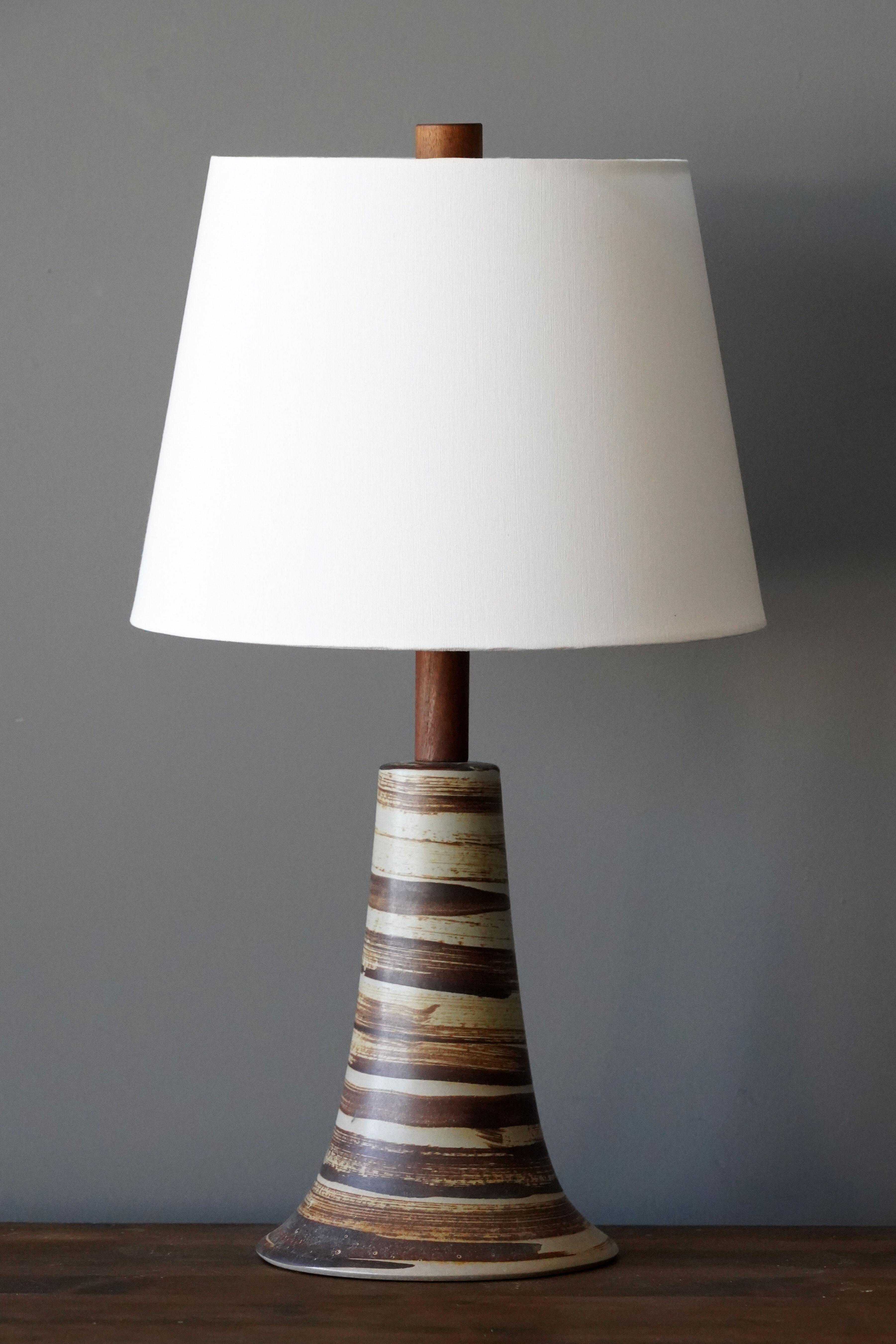 A table lamp designed by husband and wife duo Jane & Gordon Martz. Produced by Marshall Studios, Indianapolis. 

Bases are slip-cast and then dipped into glaze. Design also incorporates exquisite walnut necks and finials. Base is signed. 

Sold