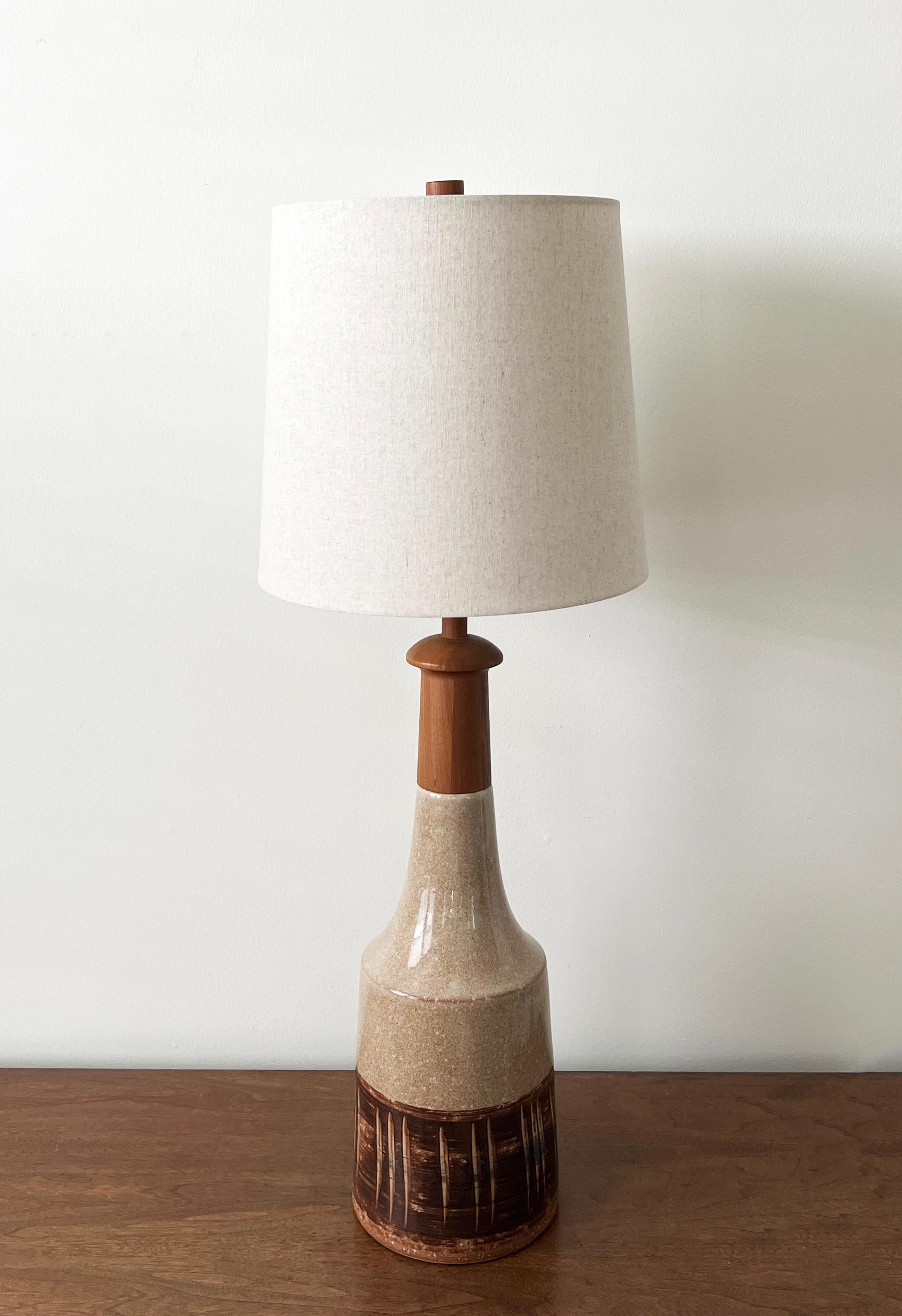 Large table lamp by famed ceramicist duo Jane and Gordon Martz, for Marshall Studios, 1960s. This lamp has interesting incised detailing with a modern earthtone pallete consisting of tans, browns, and whites. The walnut neck and finial are both in