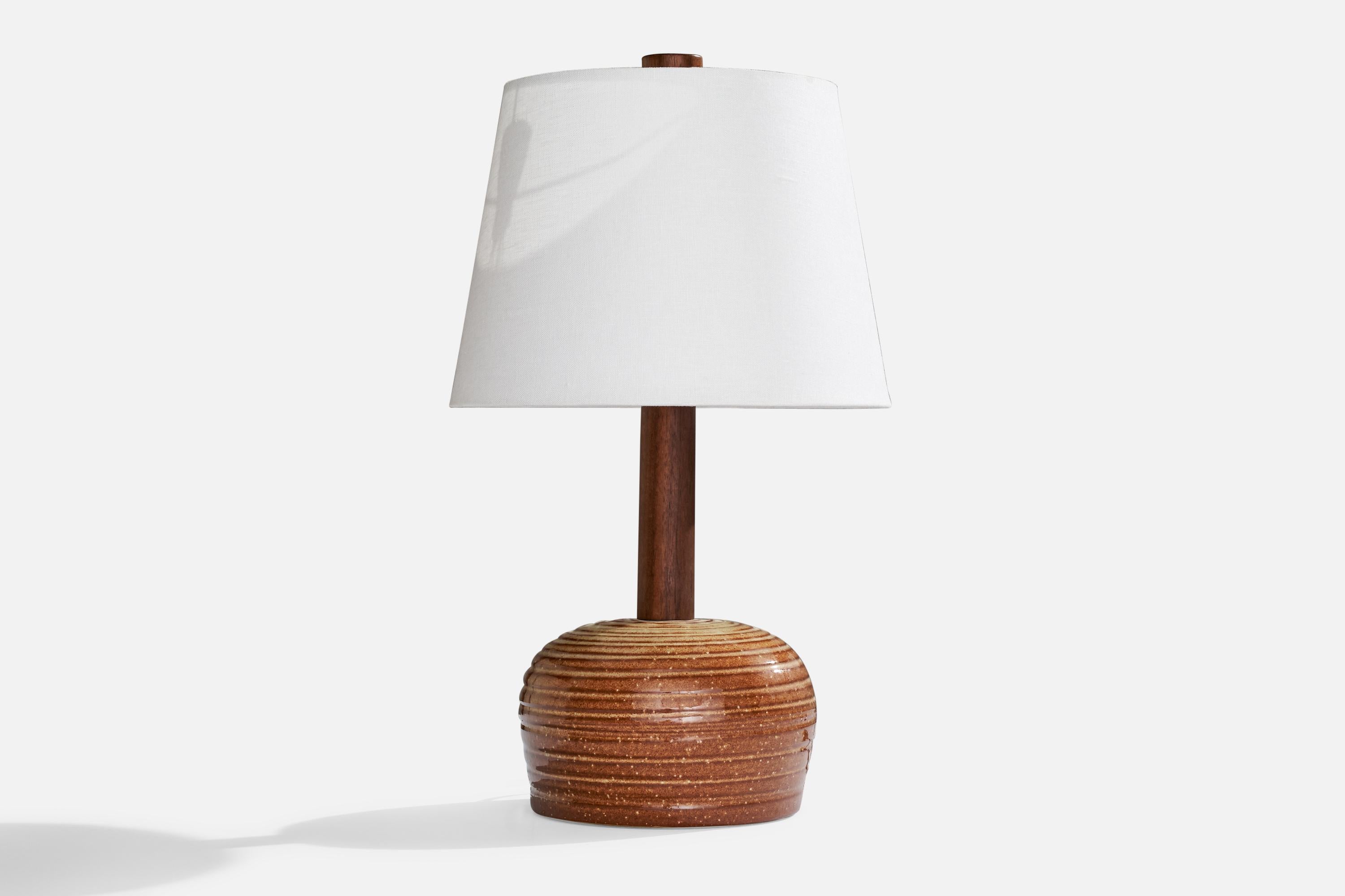 A brown red-glazed ceramic and walnut table lamp designed by Jane & Gordon Martz and produced by Marshall Studios, USA, 1960s.

Dimensions of Lamp (inches): 14” H x 8” Diameter
Dimensions of Shade (inches): 9”  Top Diameter x 12” Bottom Diameter x