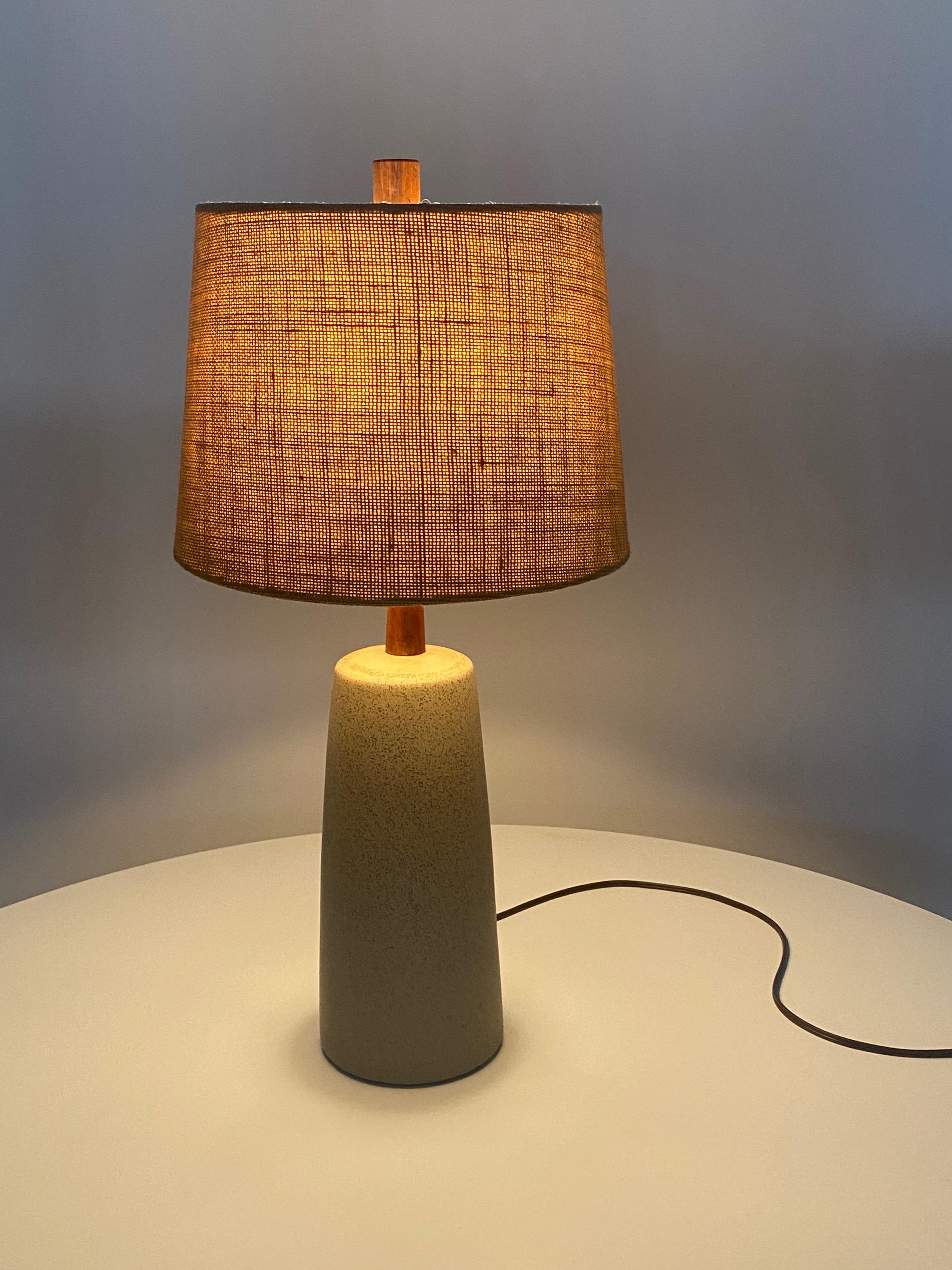 Ceramic table lamp in a light earthtone brown with dark brown speckles, with orignial teak finial and neck, created by Jane and Gordon Martz for their company, Marshall Studios. The lamp is signed on the back by the lamp cord exit, Martz. Comes with