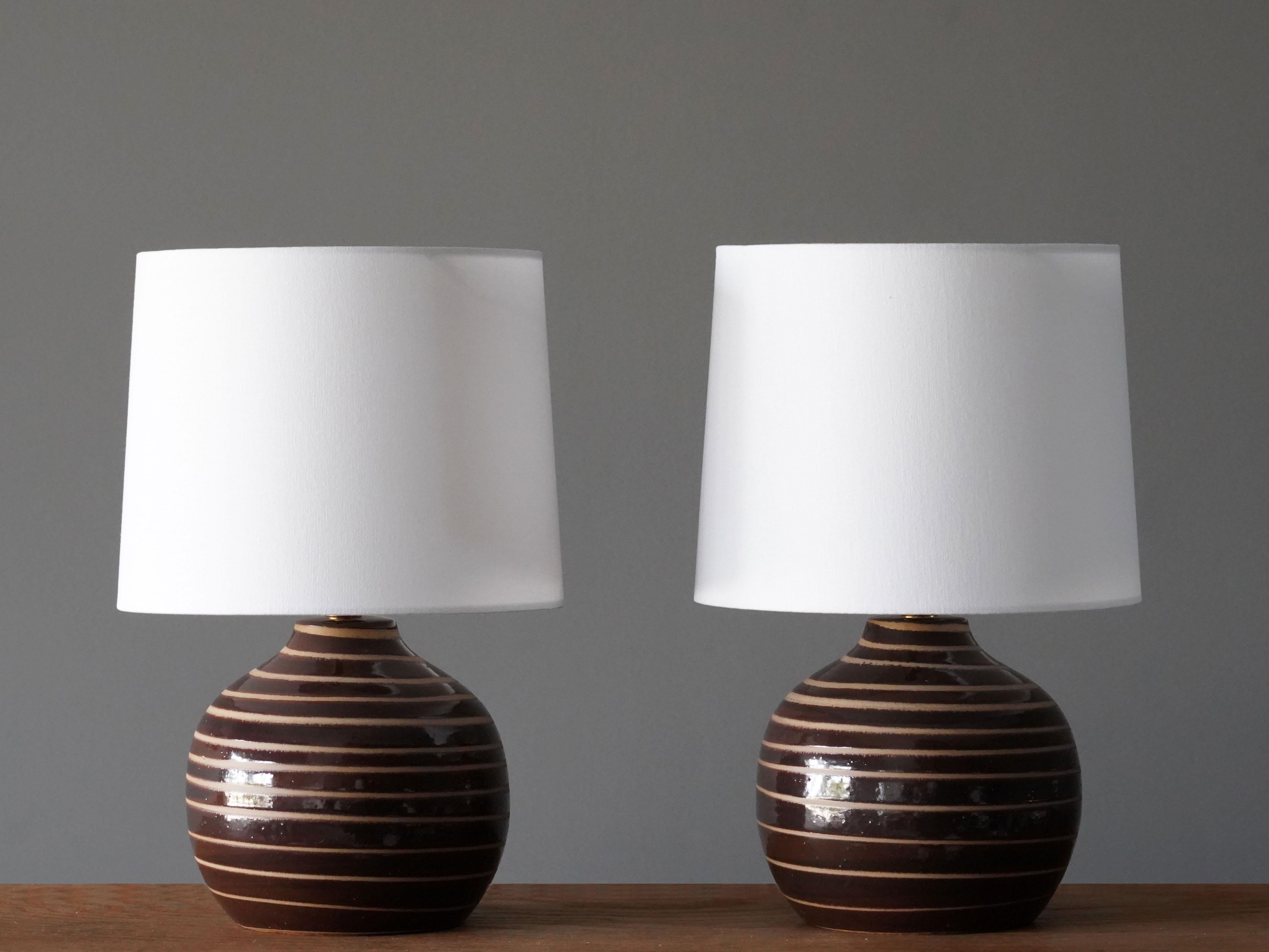 A pair of table lamps designed by husband and wife duo Jane & Gordon Martz. Produced by Marshall Studios, Indianapolis. 

The base is slip-cast and then dipped into glaze and hand painted. Base is signed. Sold without lampshades.

Jane & Gordon